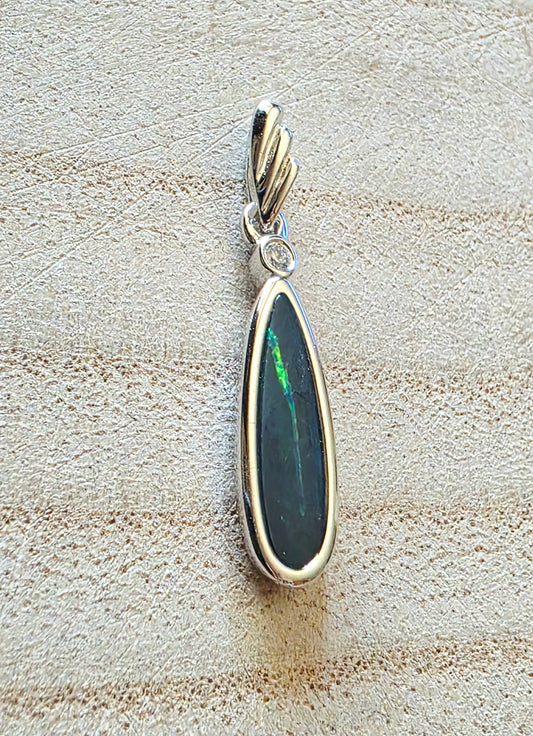 Opal pendant with silver setting on a textured beige surface