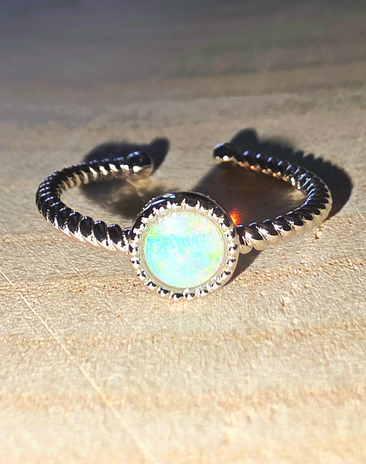 Ring with opal stone and band on a beige surface