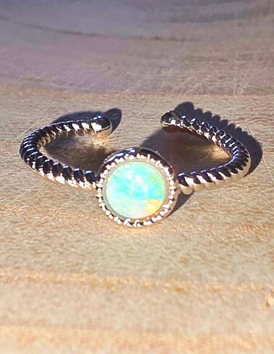 Silver ring with a central opal on a beige fabric background