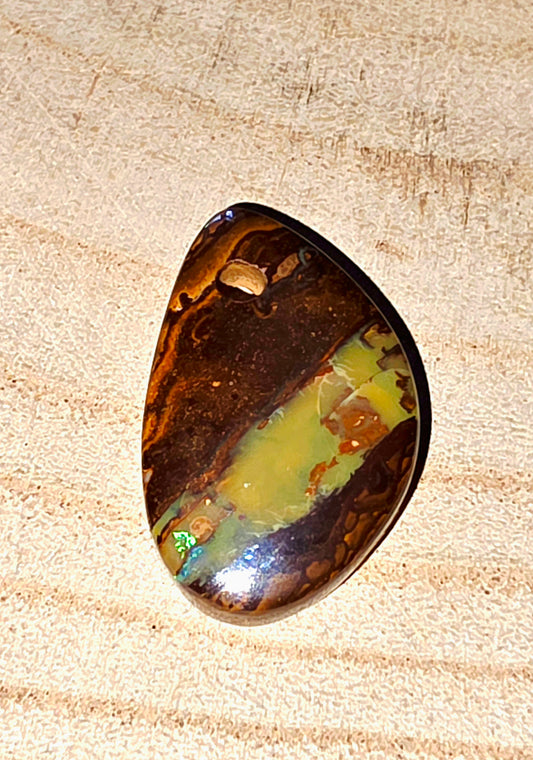 Polished opal stone on a wooden surface