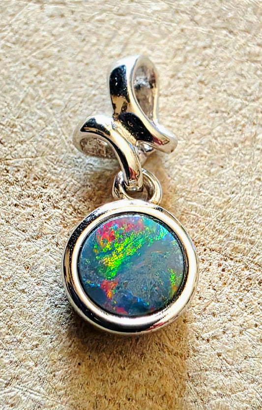 Silver pendant with a colourful opal on a textured beige background