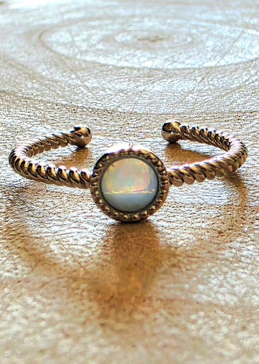 Ring with opal stone and braided design on a textured surface