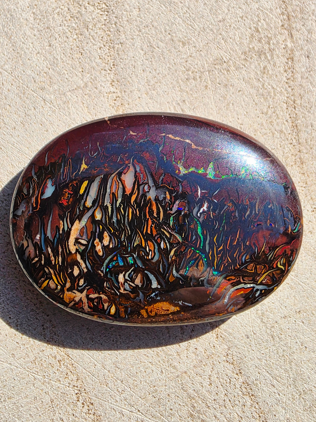 A boulder opal cabochon displaying full tribal patterns