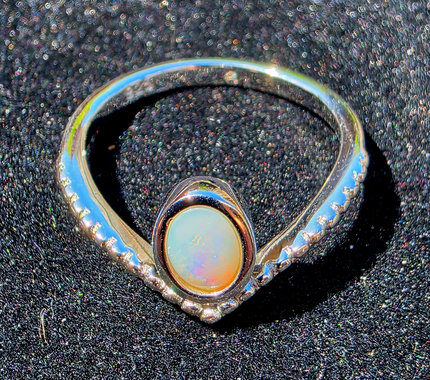 Silver ring with a central opal stone on a dark textured background