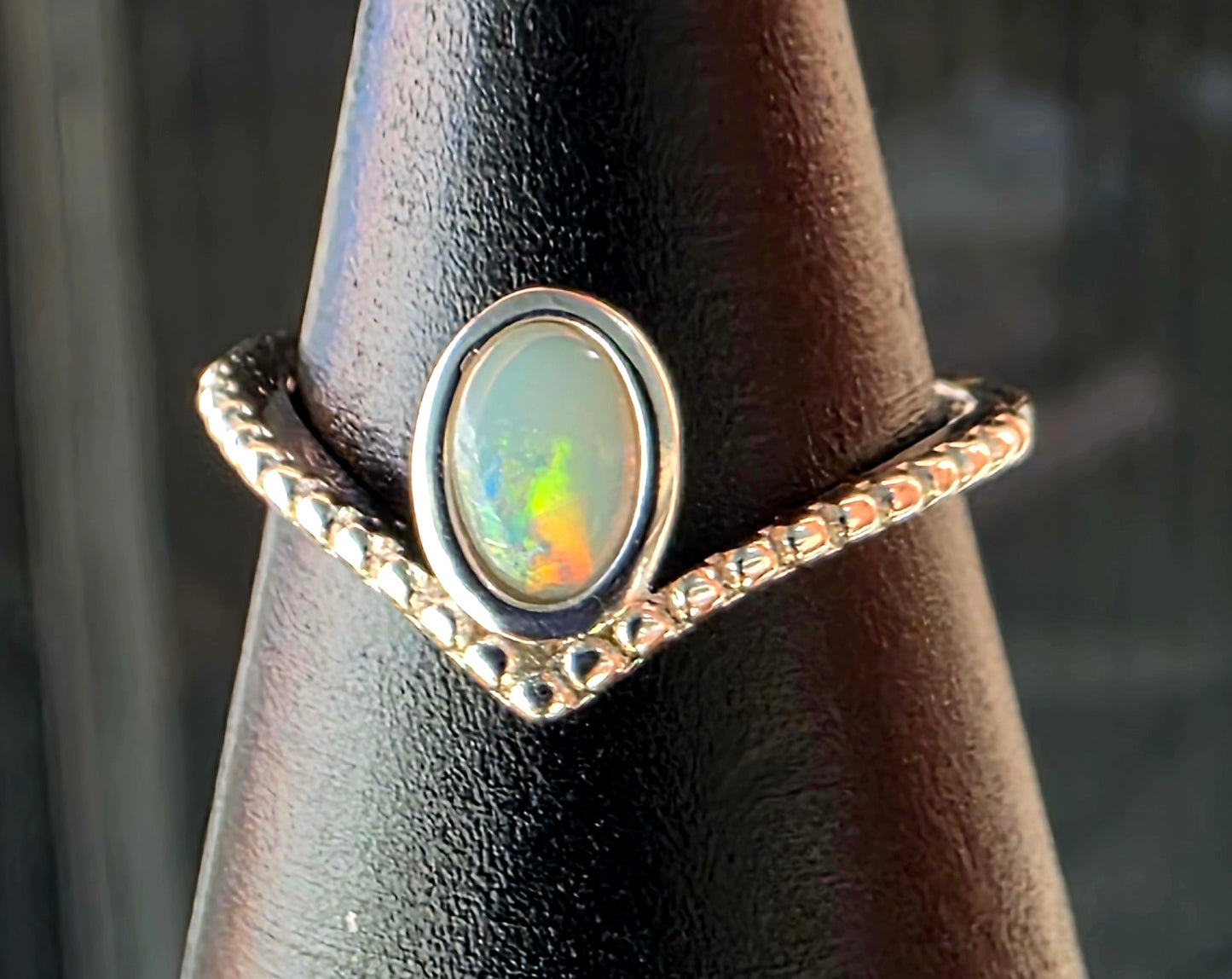 Ring with an opal stone on a black stand