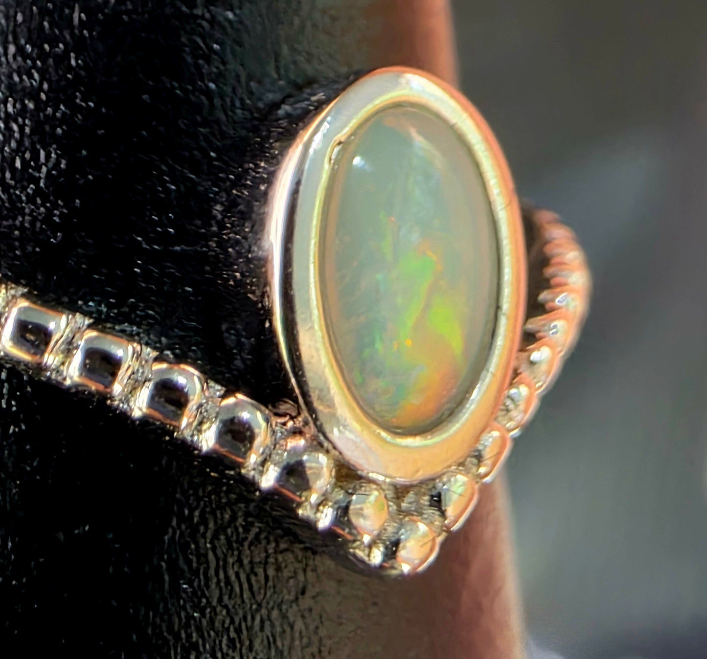Ring with an opal stone and silver border on a black stand