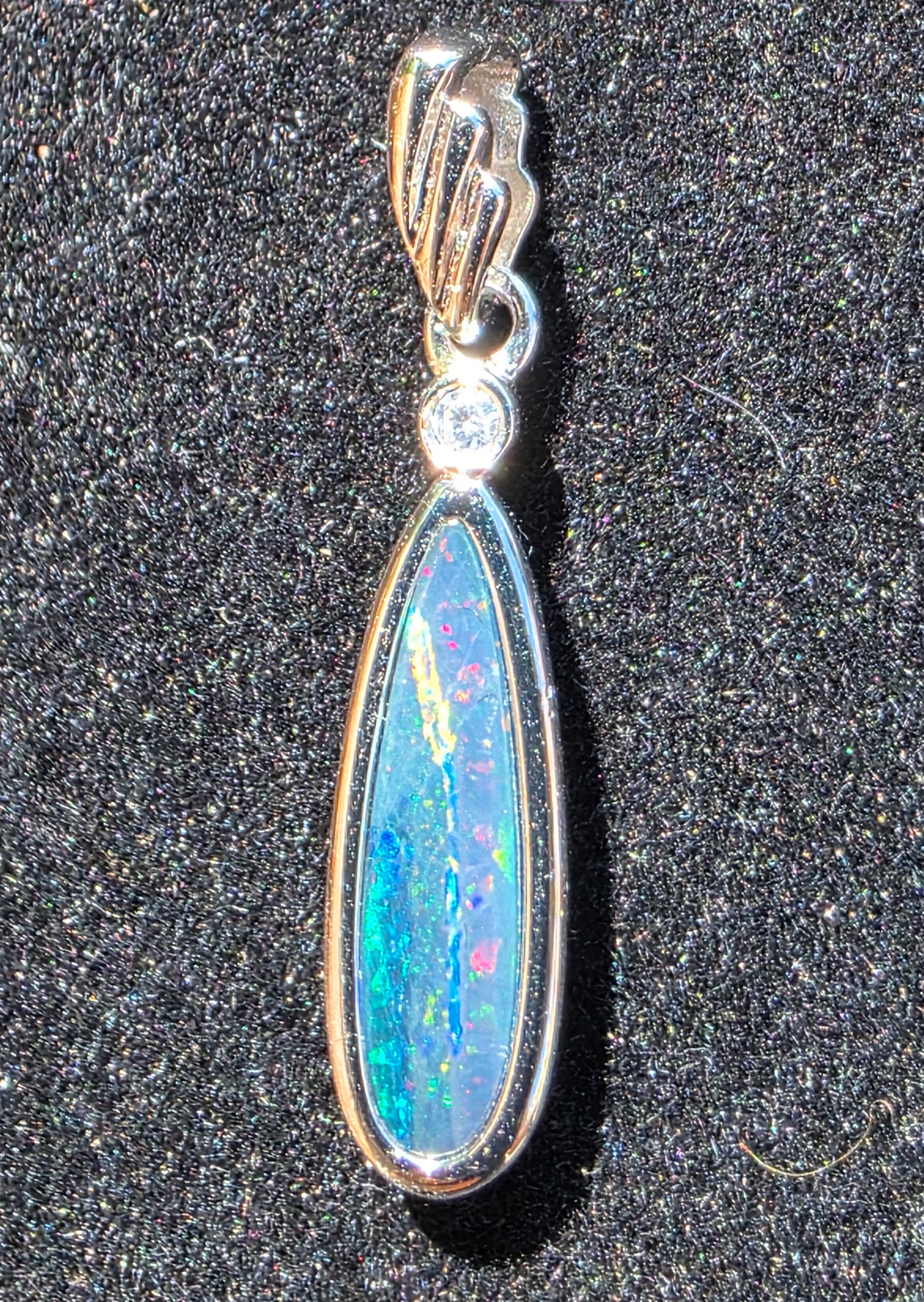 Opal pendant with silver setting on a dark textured background