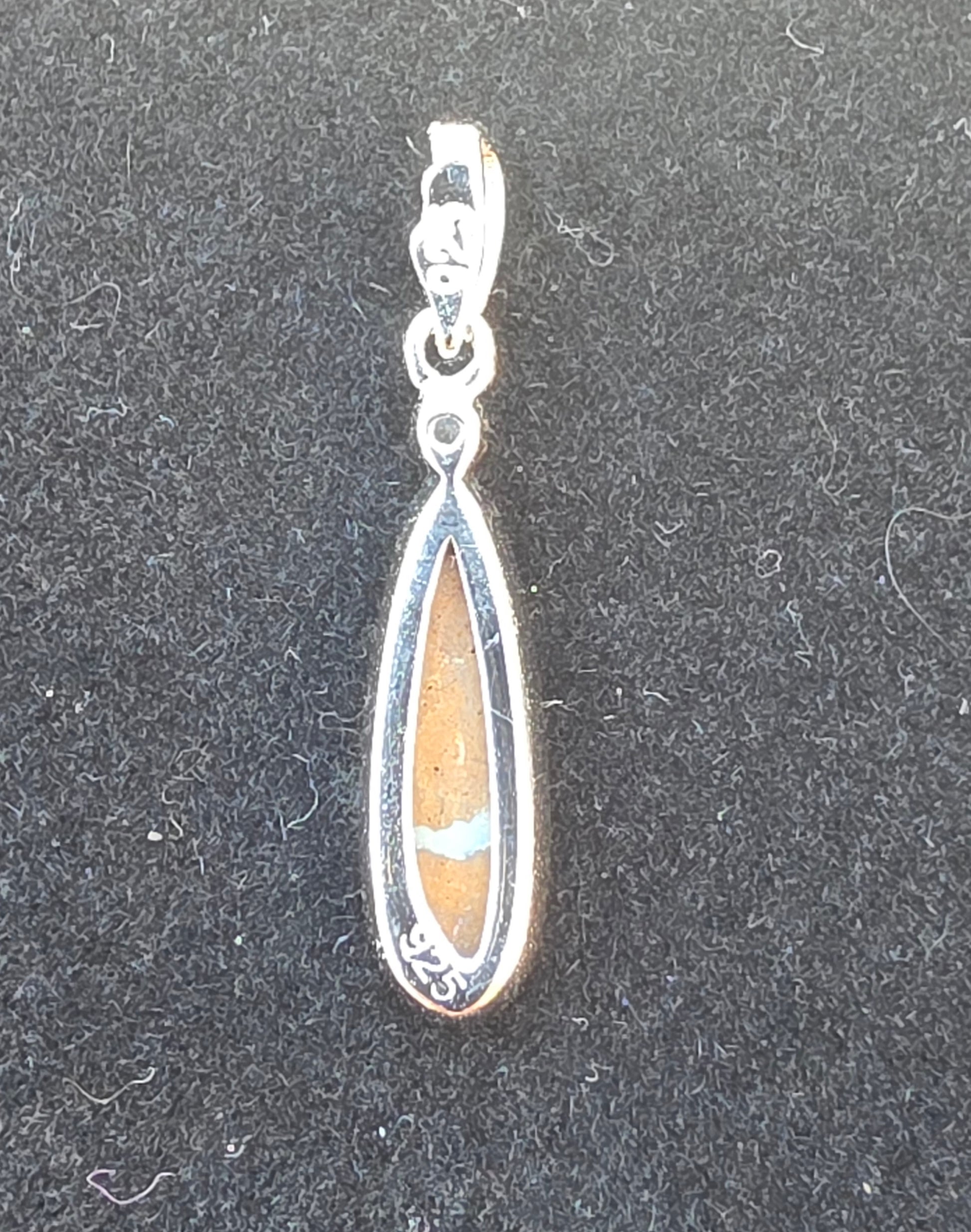 Teardrop-shaped pendant with a central stone on a dark background