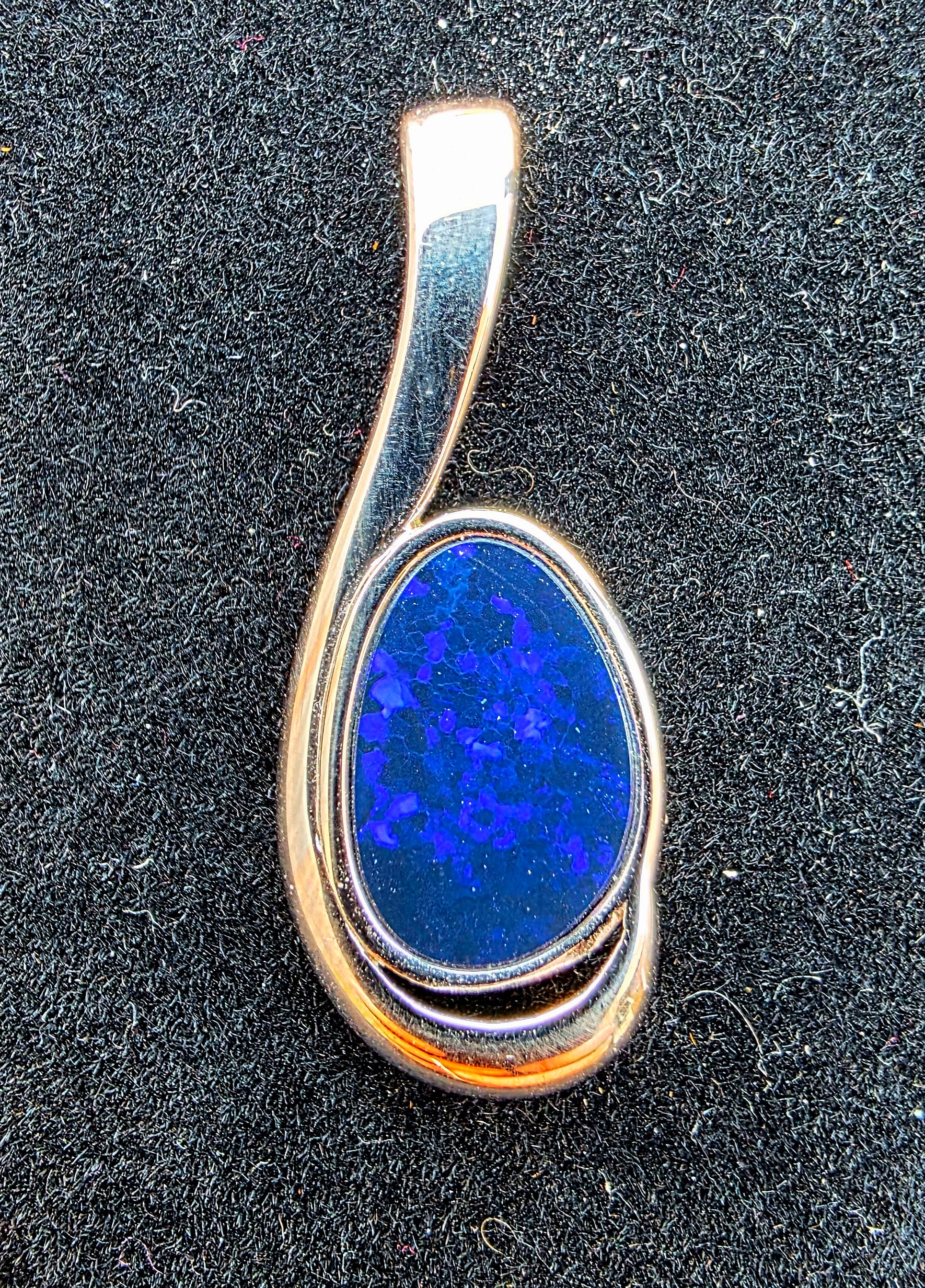 Silver pendant with a blue stone on a black background