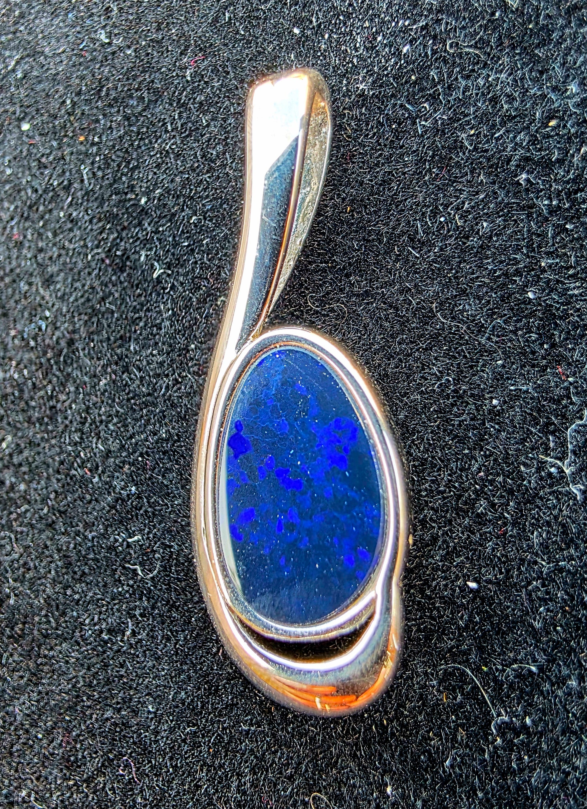 Silver opal pendant with a blue stone on a black background