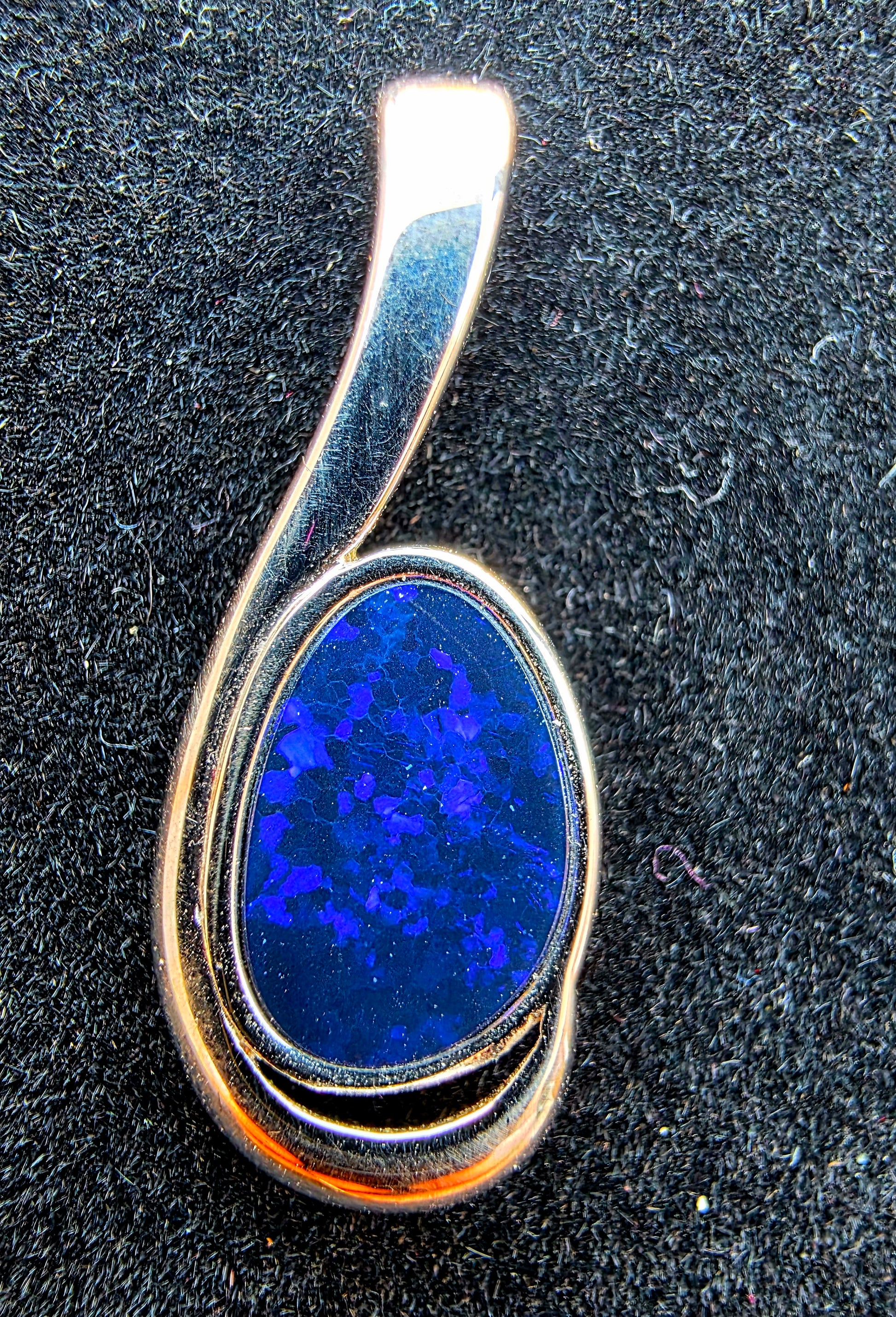 Silver pendant with a blue stone on a dark textured background