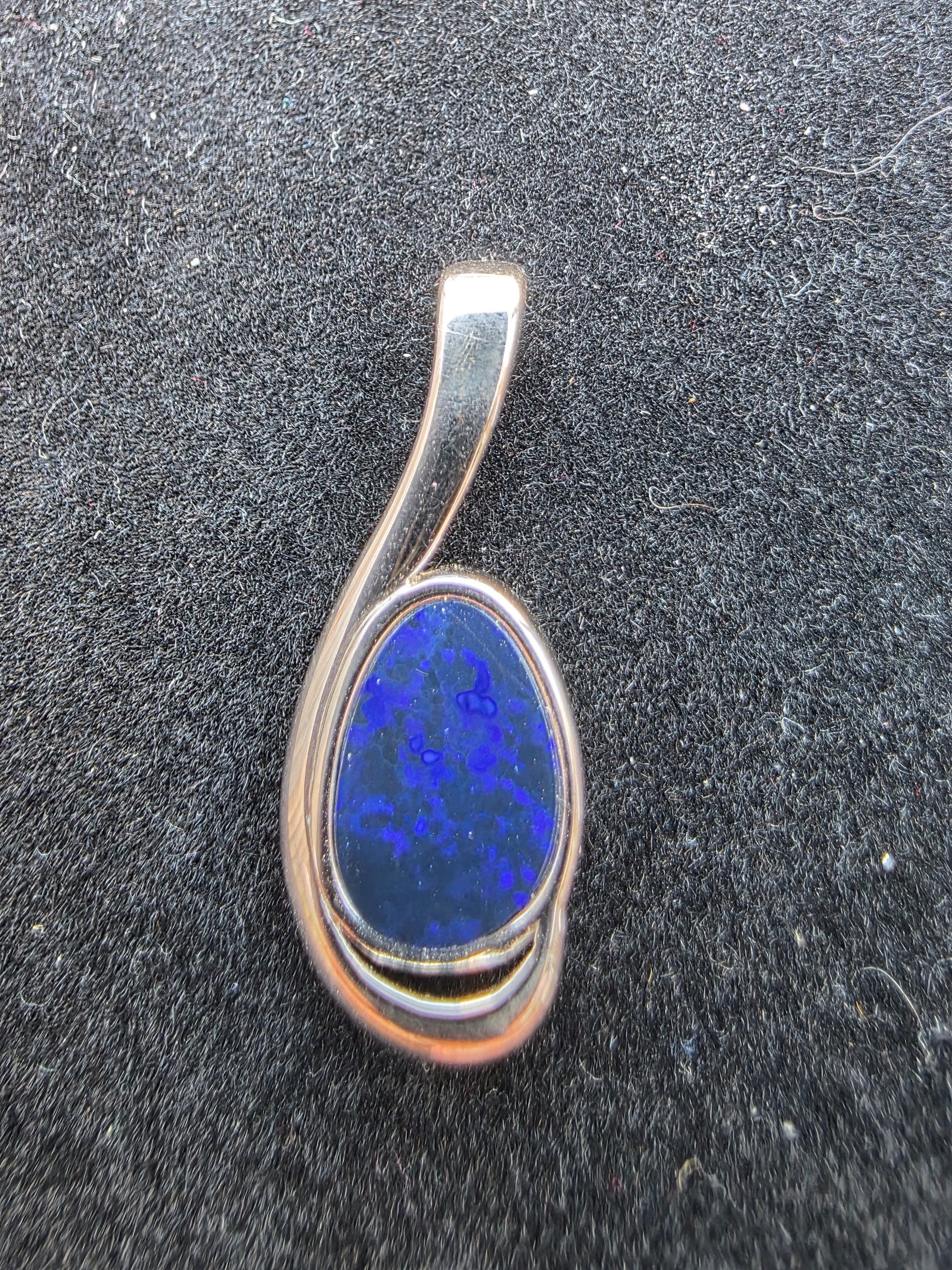 Silver pendant with a blue stone on a dark textured background