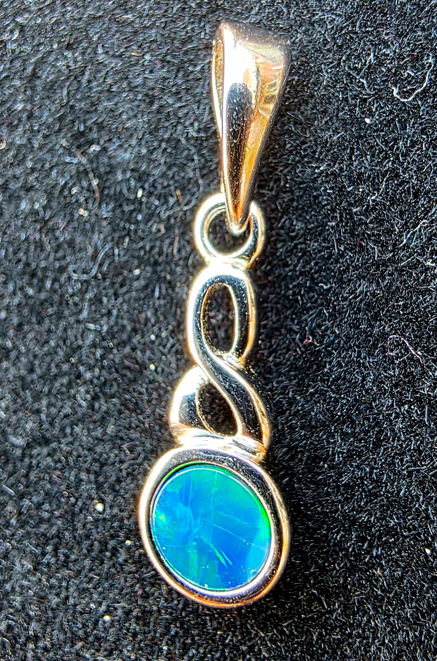 Opal pendant with silver setting on a black textured background