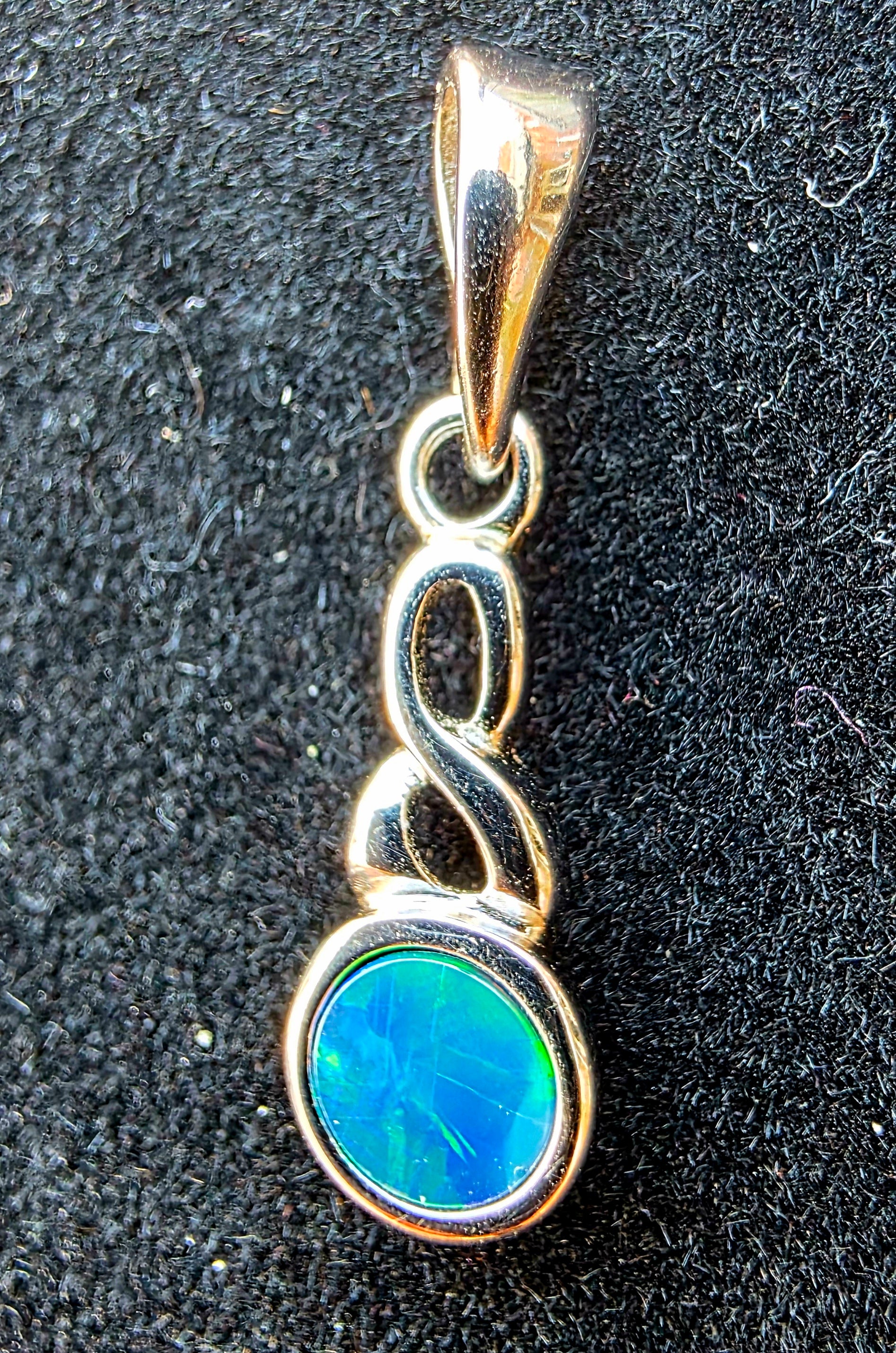 Opal pendant with silver setting on a black textured background