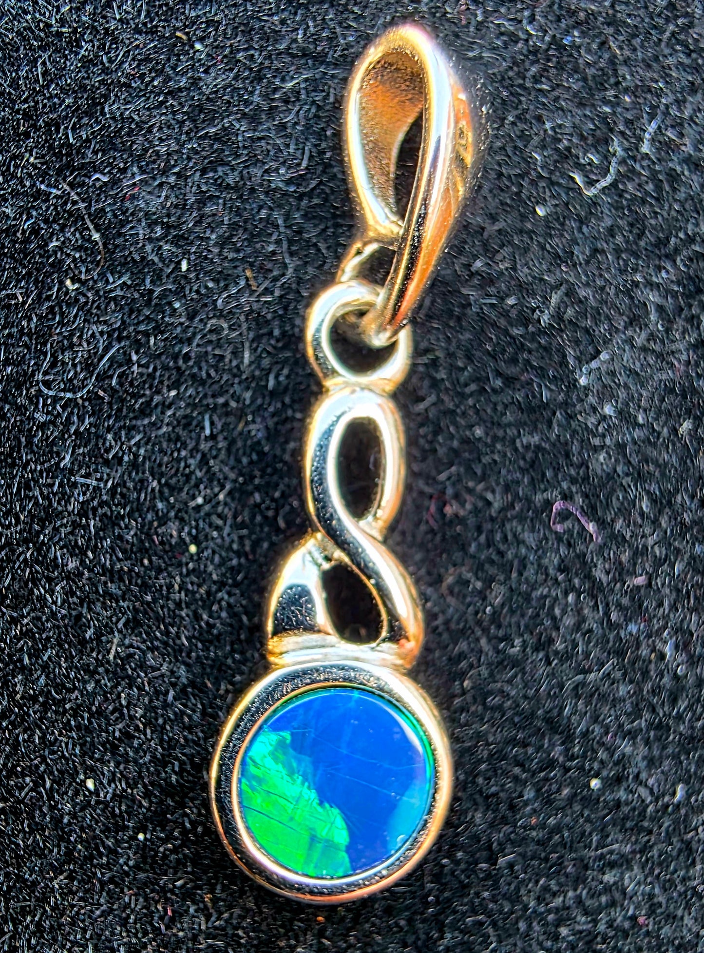 Silver pendant with a blue and green gemstone on a black background