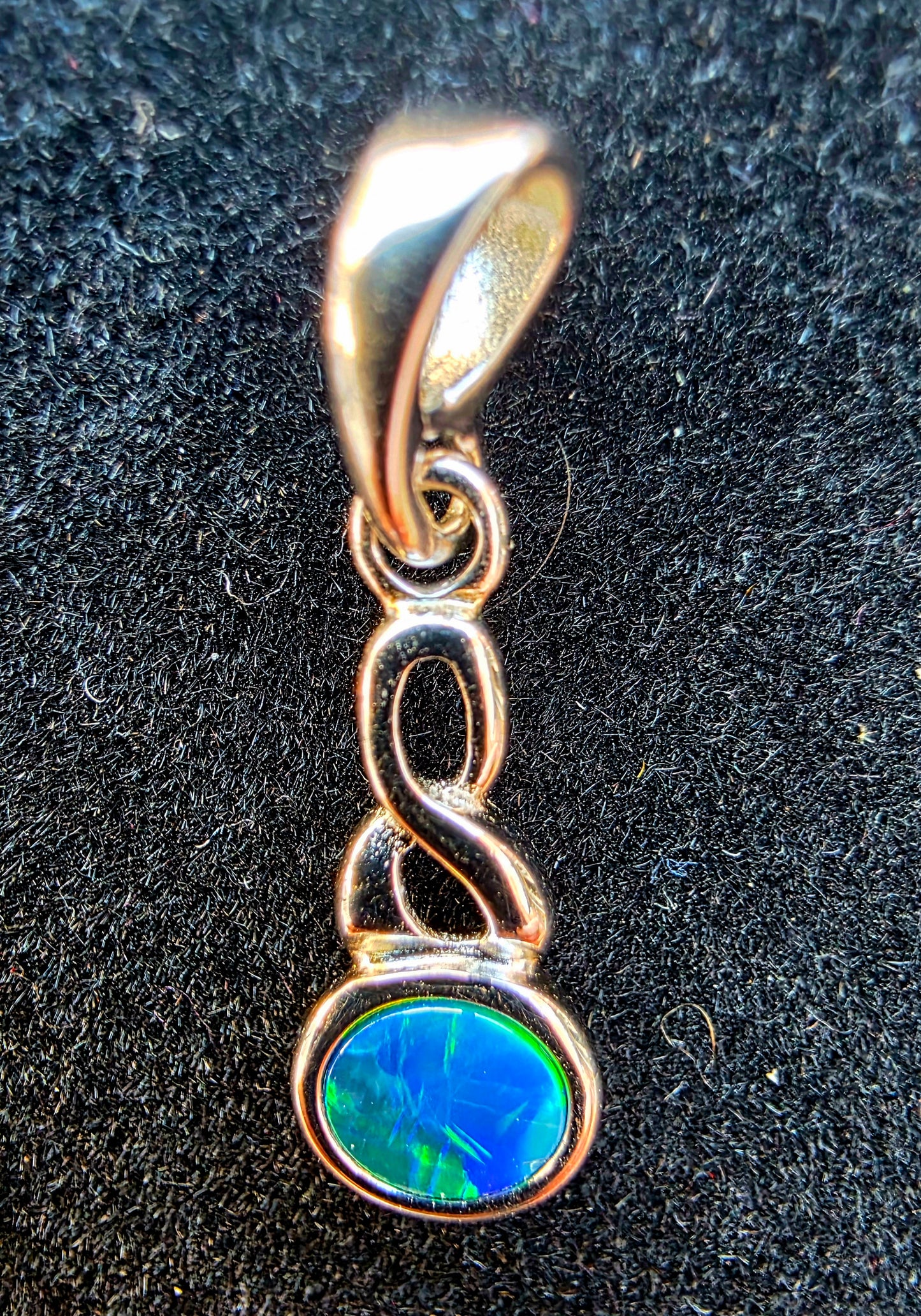 Silver pendant with a blue gemstone on a black background