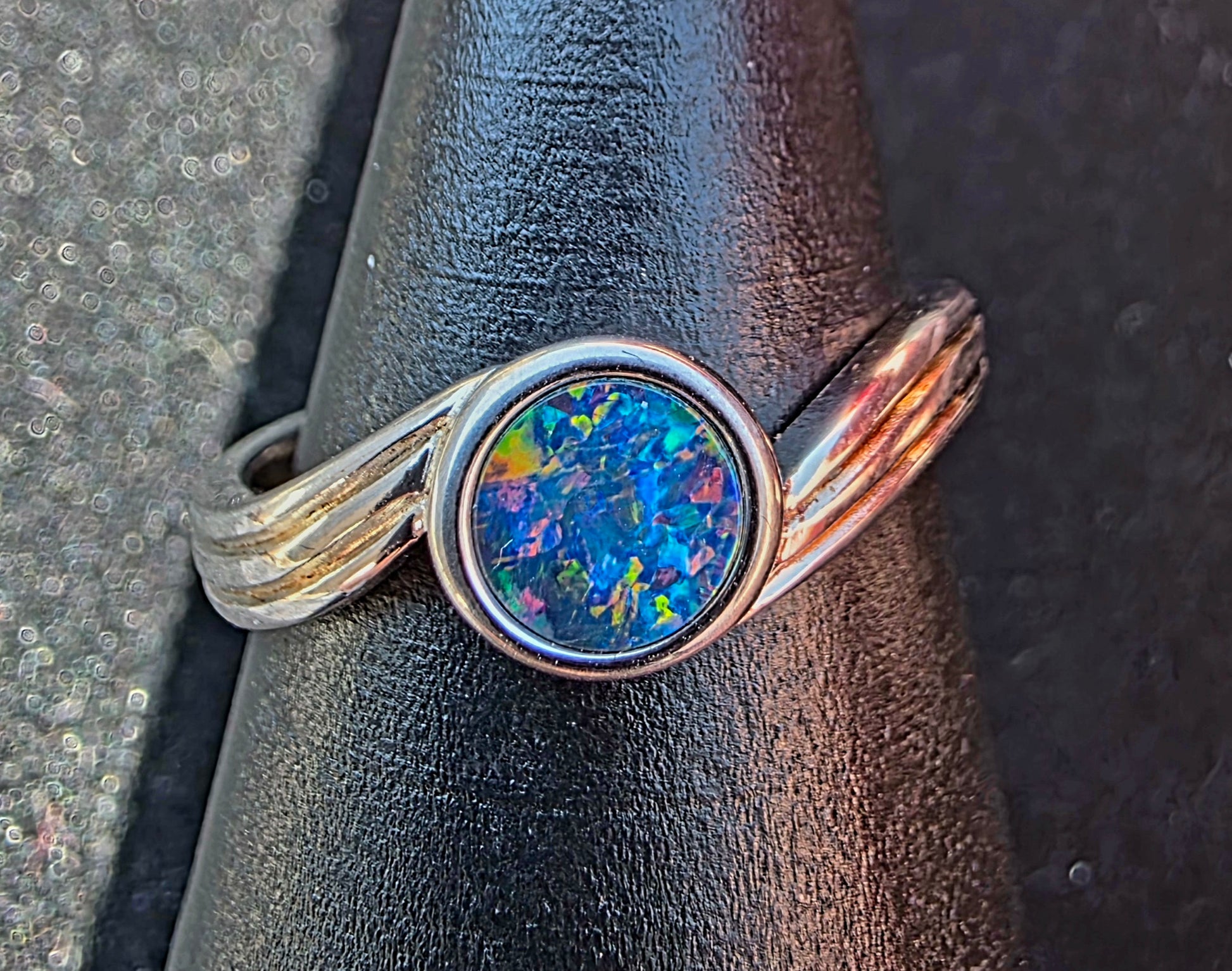 Ring with a colourful opal gemstone on a textured surface