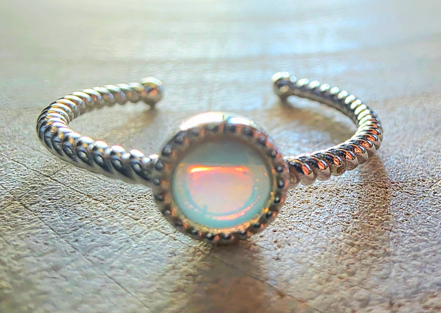 Silver ring with a glowing gemstone on a textured surface