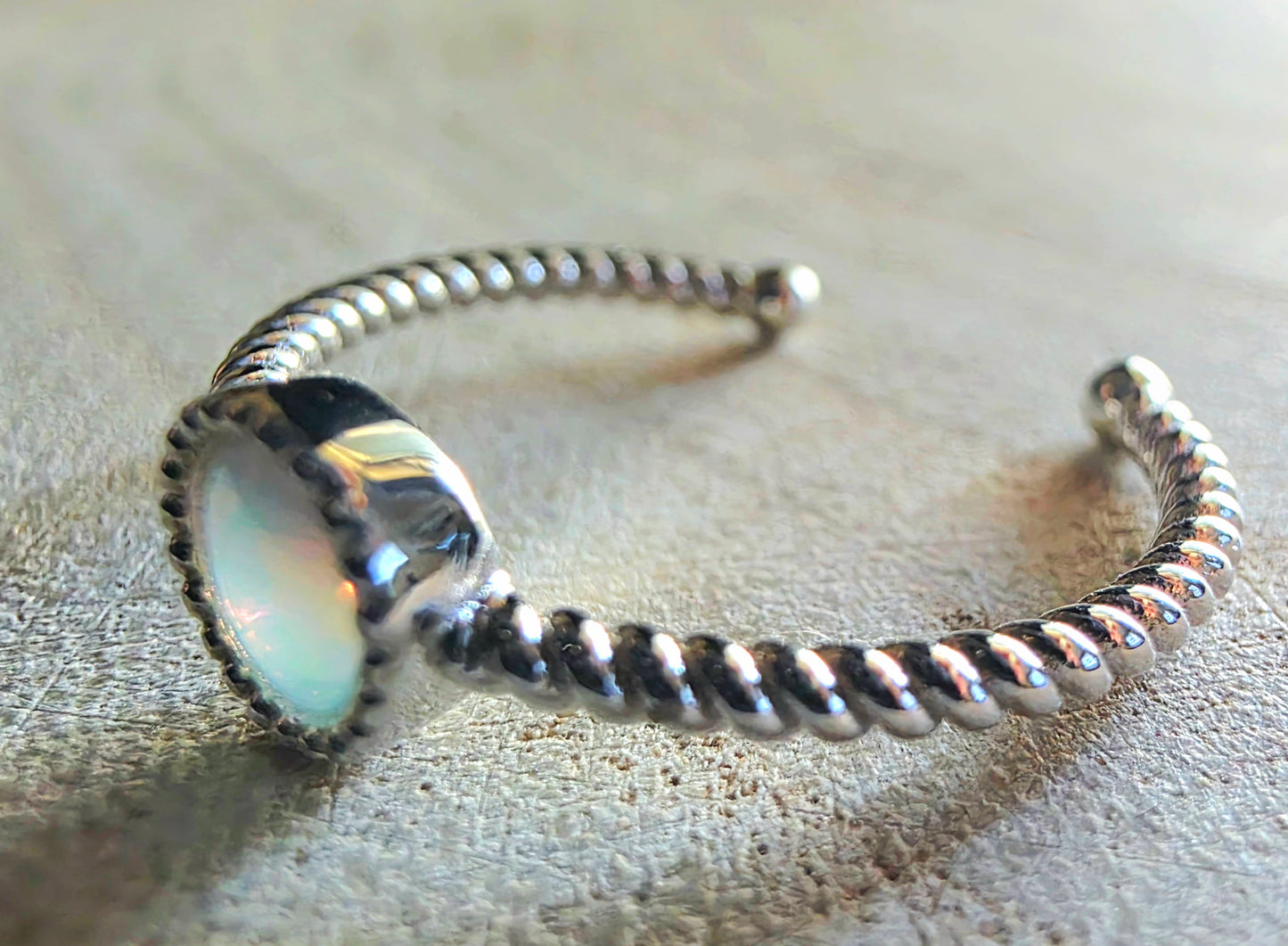 Silver ring with a circular opal on a textured surface