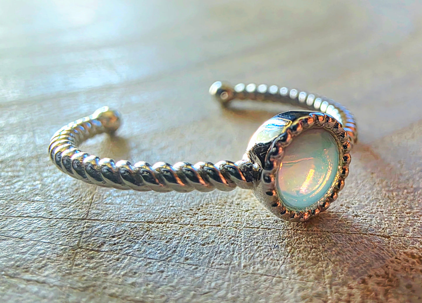 Silver ring with a light opal stone on a wooden surface