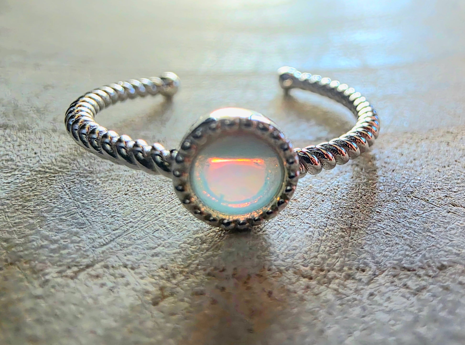 Silver ring with an opal stone on a textured surface