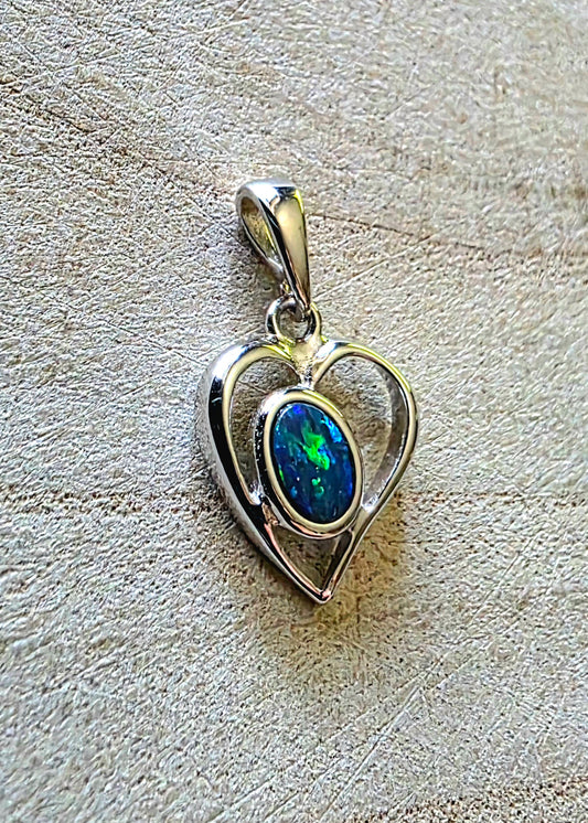Heart-shaped pendant with a blue boulder opal on a textured beige background