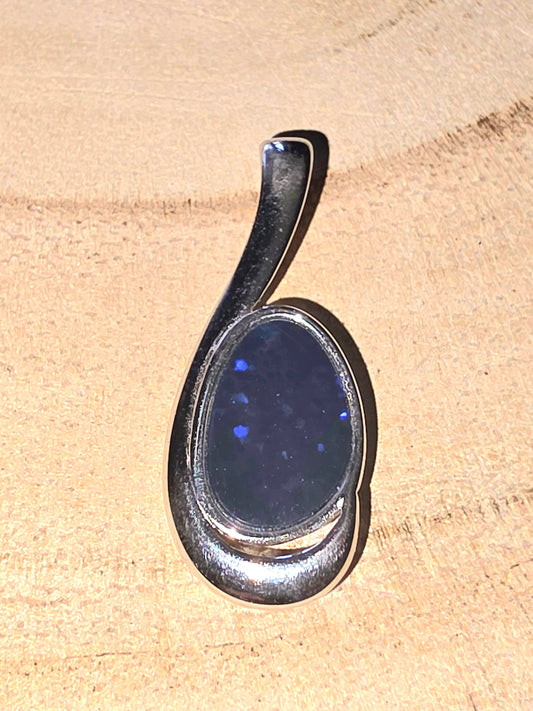 Silver pendant with a blue stone on a beige background