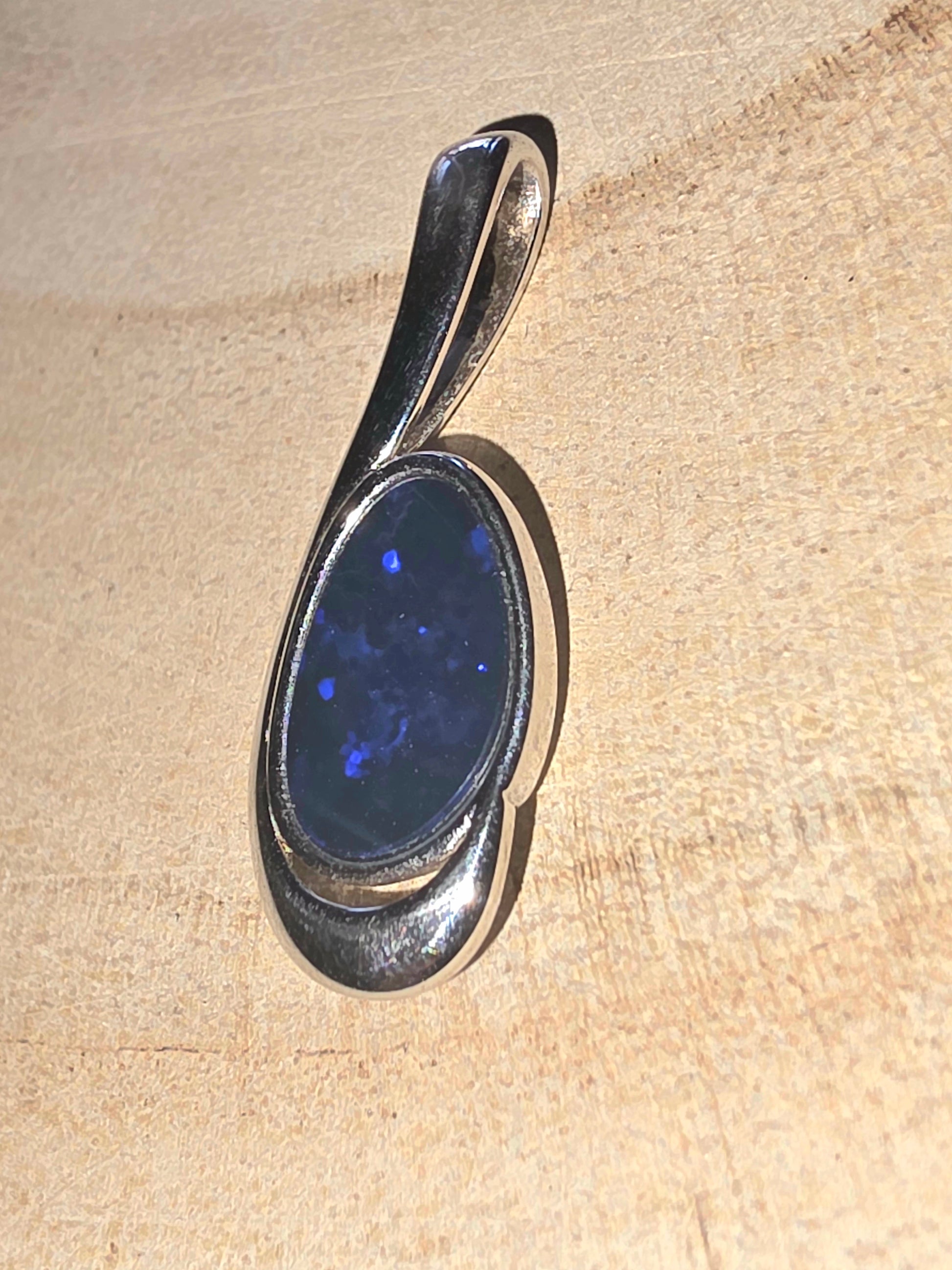 Silver pendant with a blue opal on a beige background