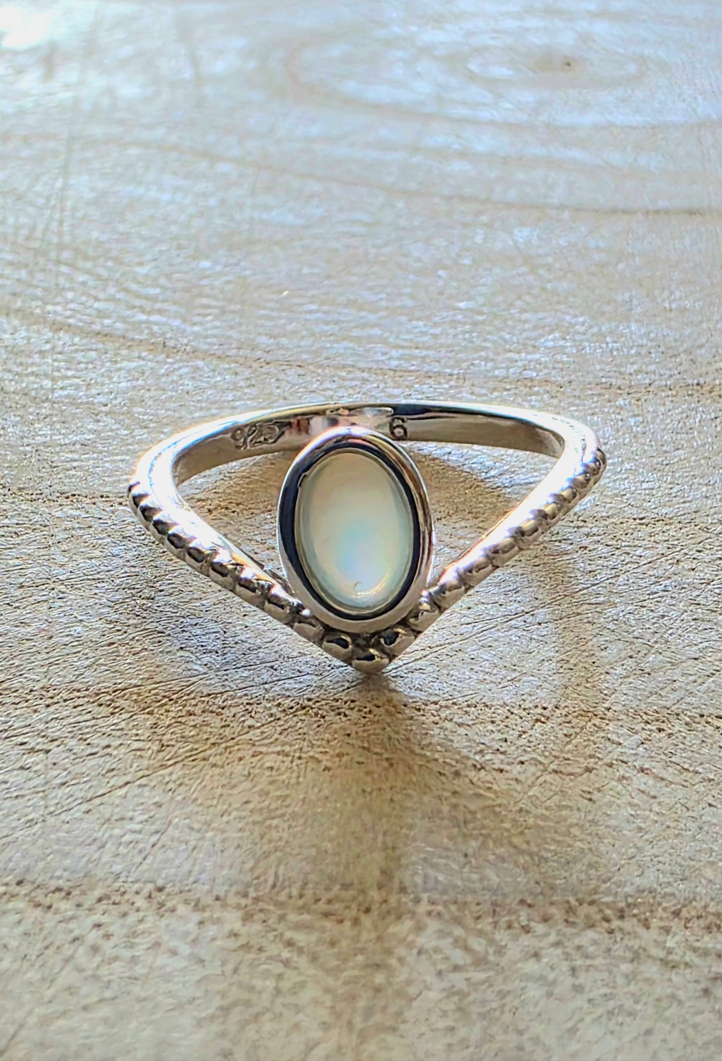 Silver ring with a central gemstone on a wooden surface