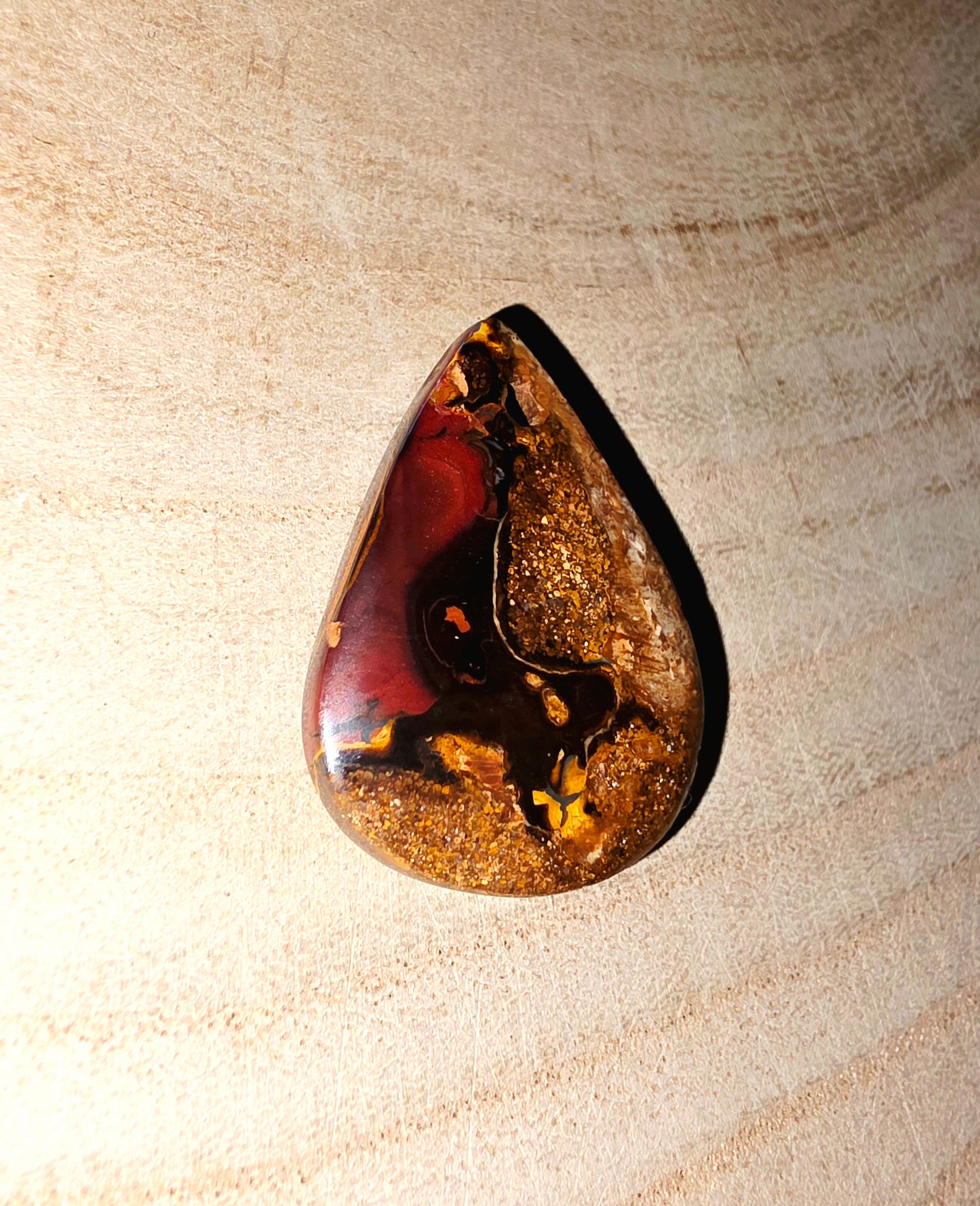 Teardrop-shaped stone on a beige textured background