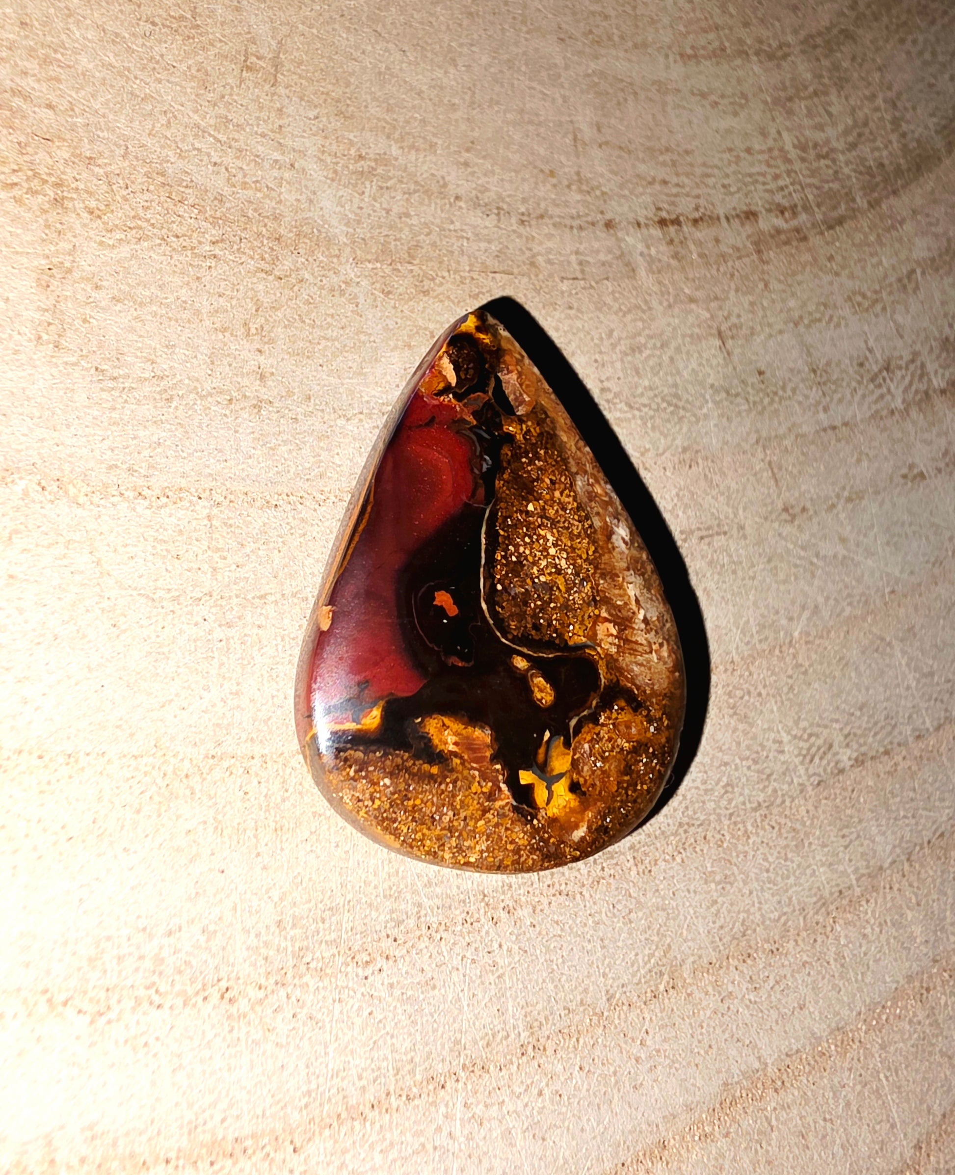 Teardrop-shaped stone on a beige textured background