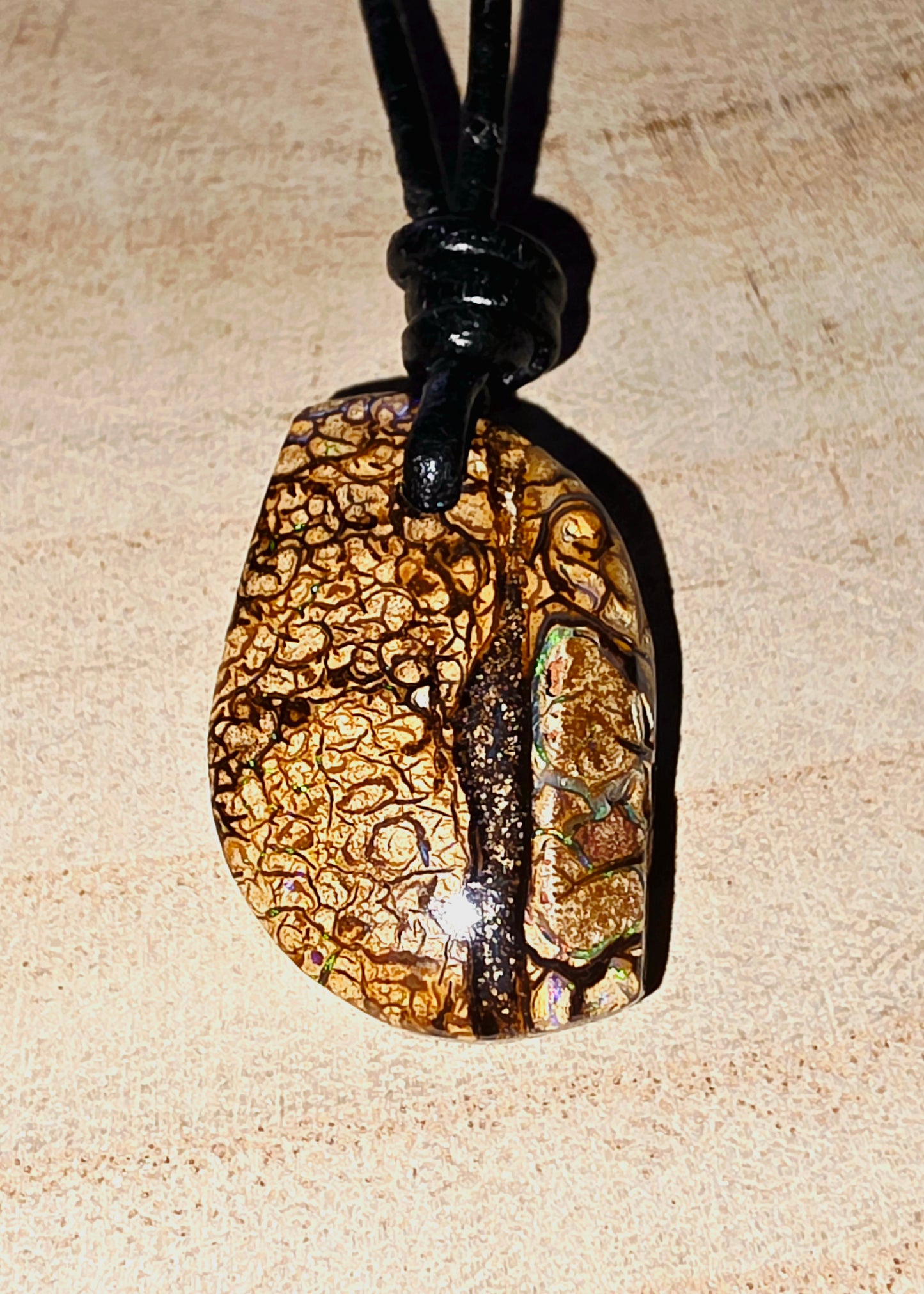Pendant necklace with a textured stone design on a beige background