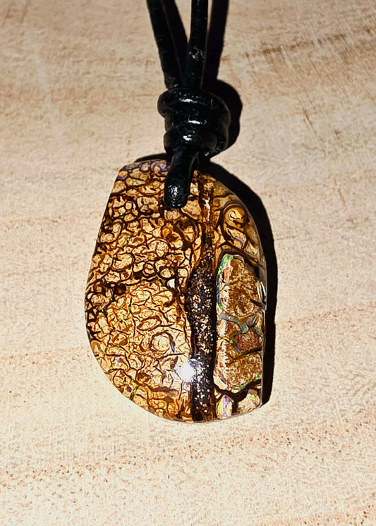 Pendant necklace with a textured stone design on a beige background