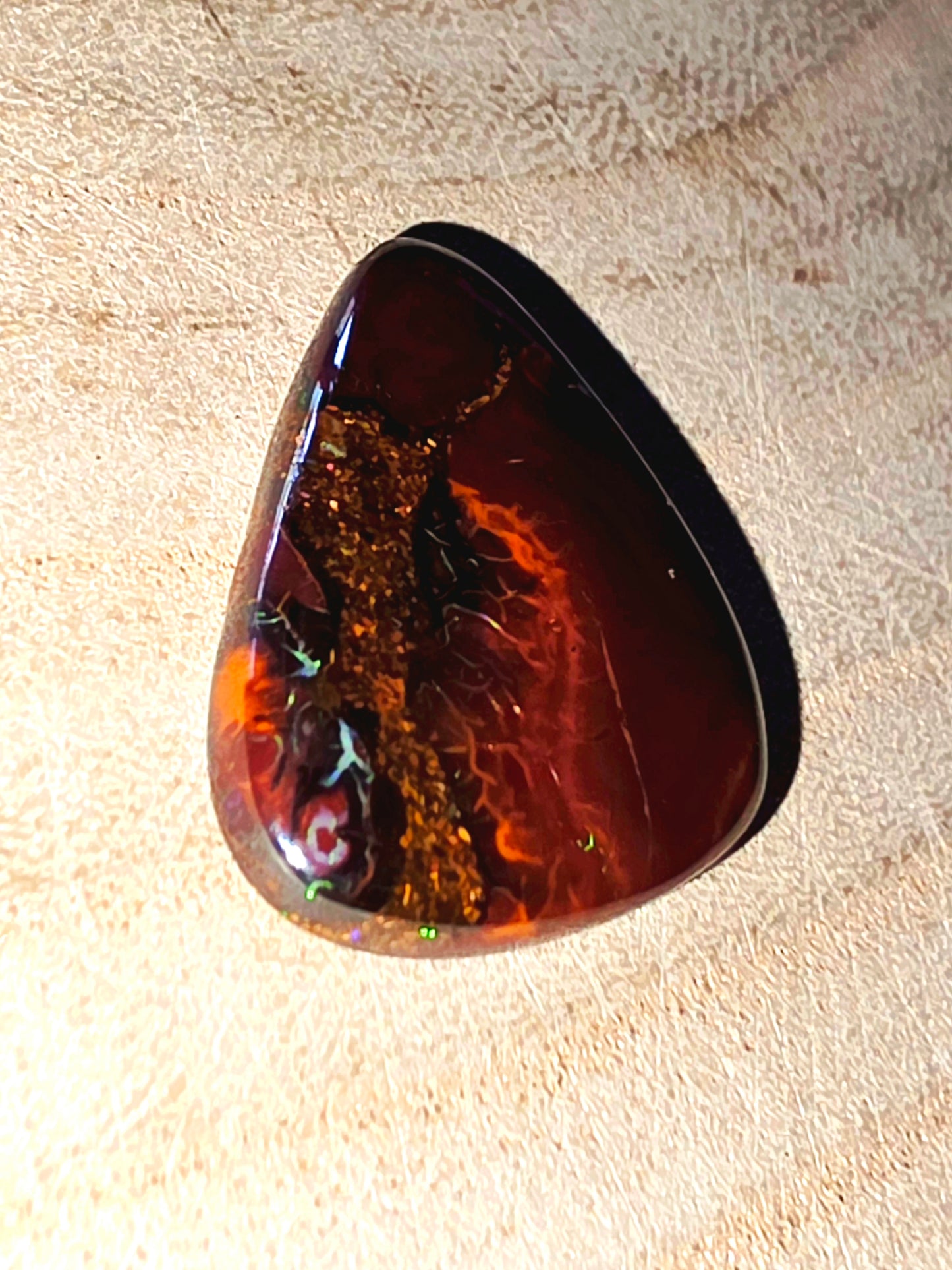 Polished opal stone on a textured beige background