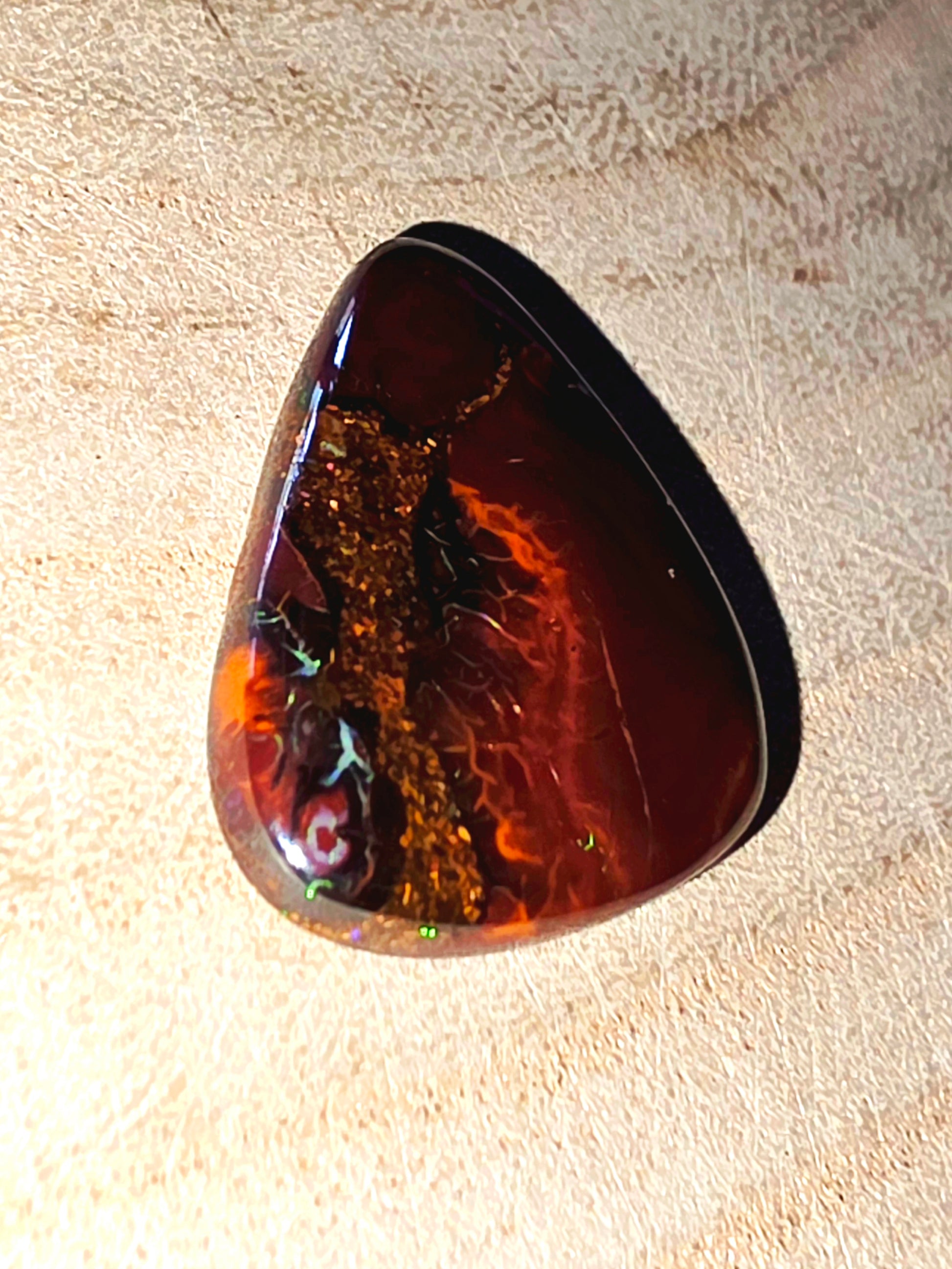 Polished opal stone on a textured beige background