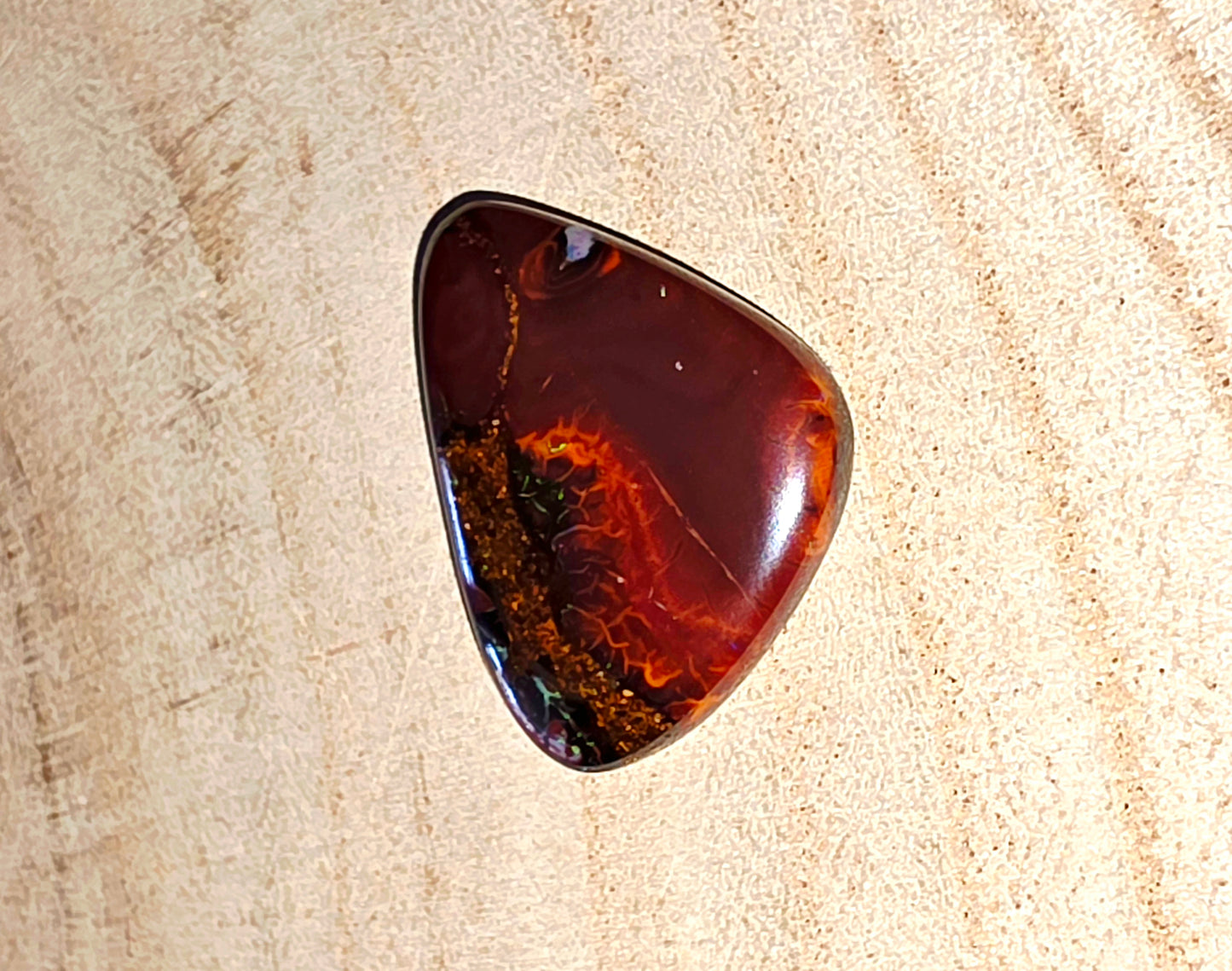 Polished opal stone on a beige wood background