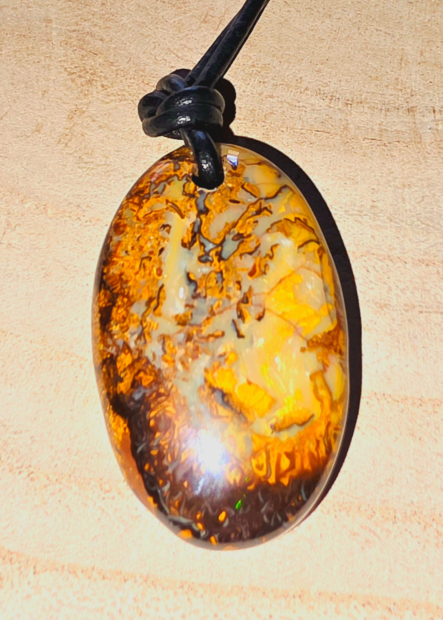 Oval-shaped opal pendant on a beige background