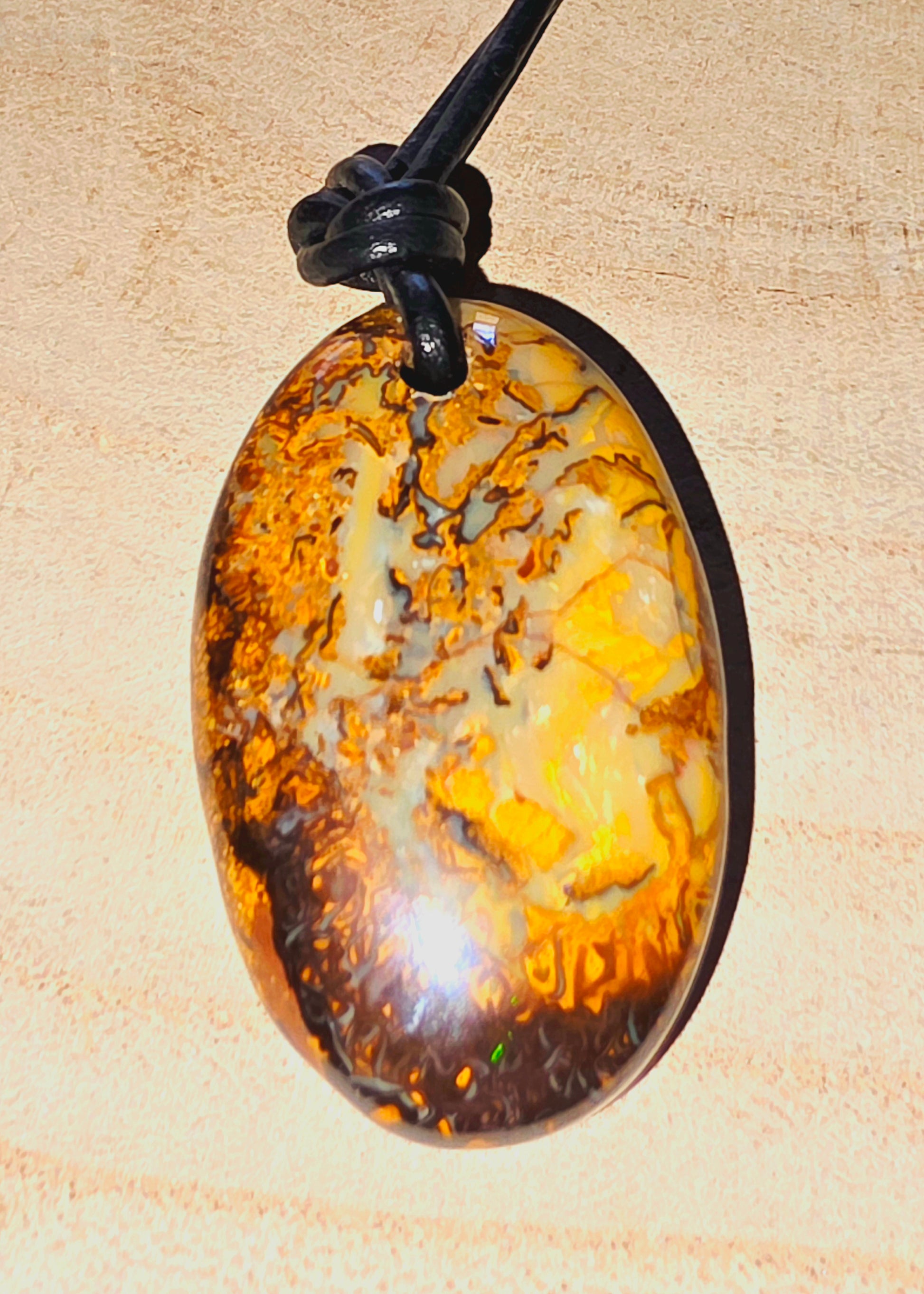 Oval-shaped opal pendant on a beige background
