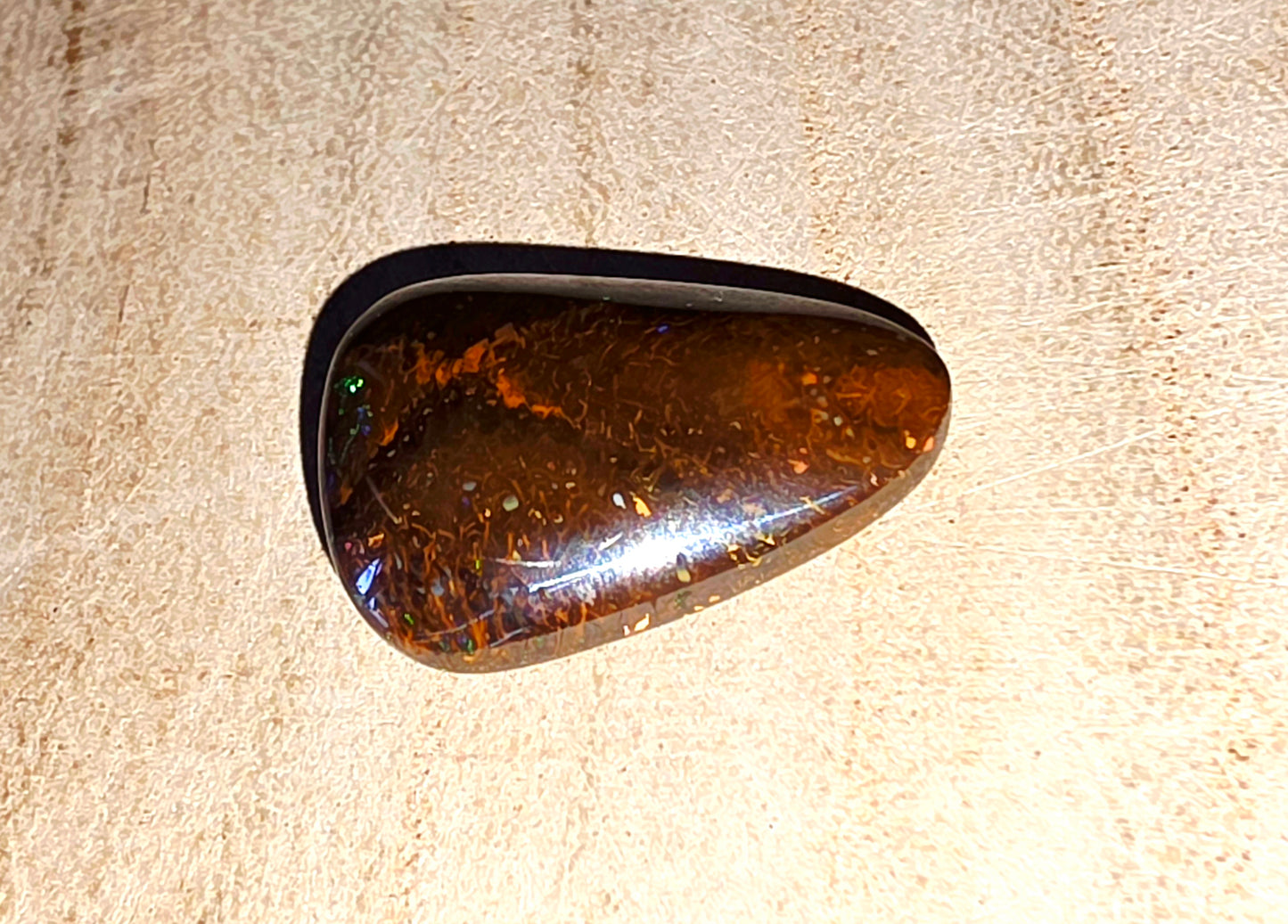Polished opal stone on a beige background