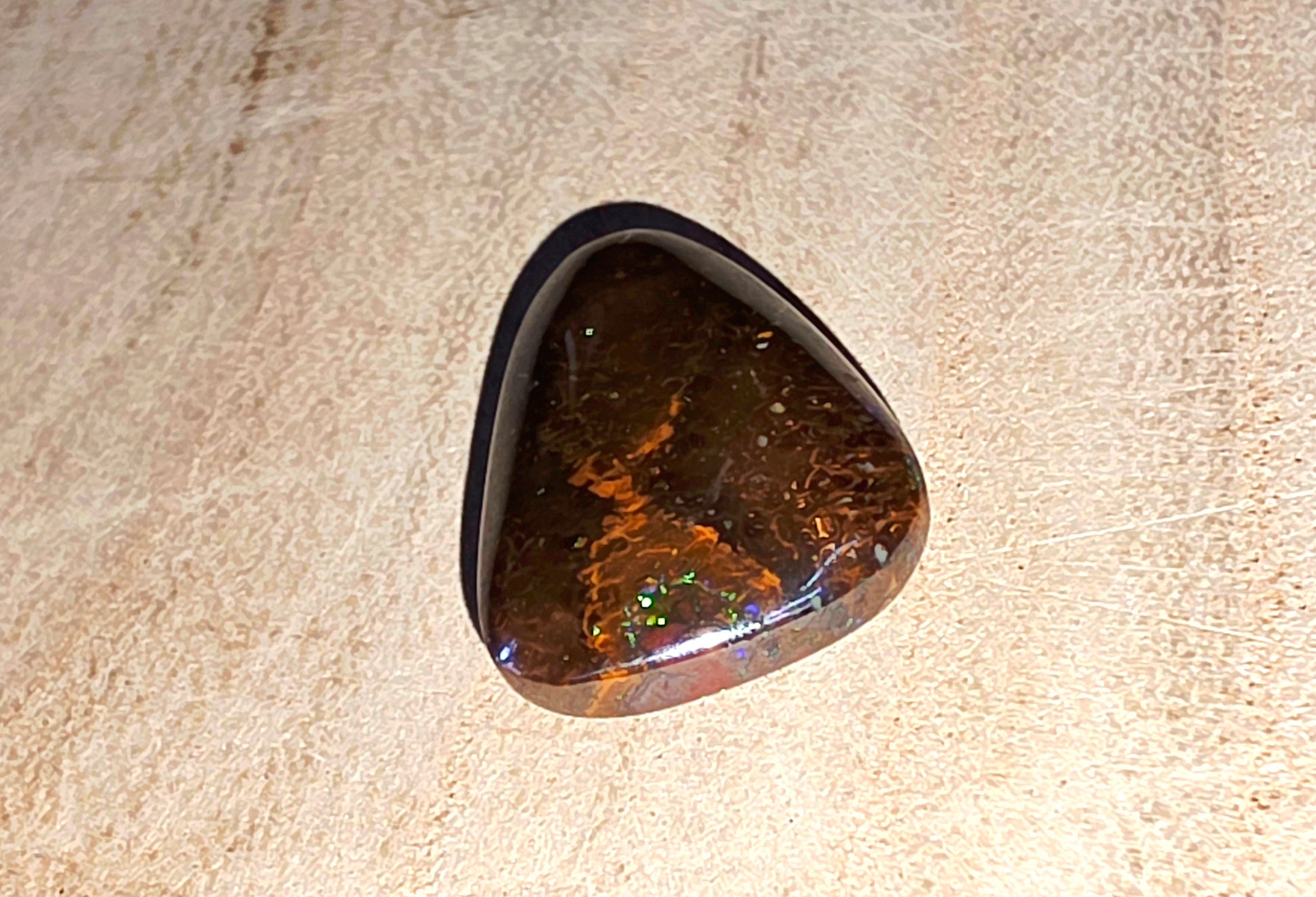 Polished opal stone on a beige background