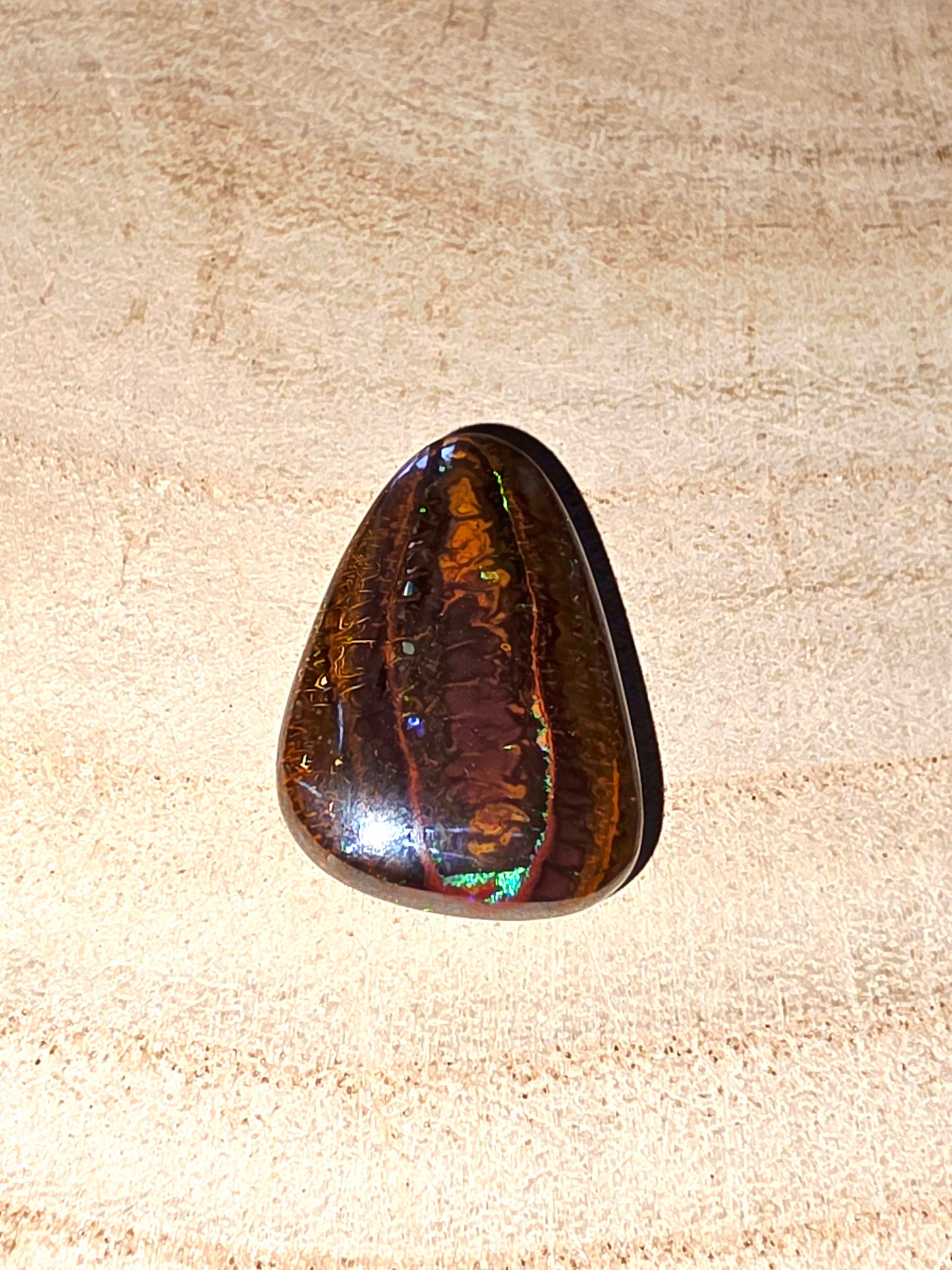 Polished gemstone on a beige wood background