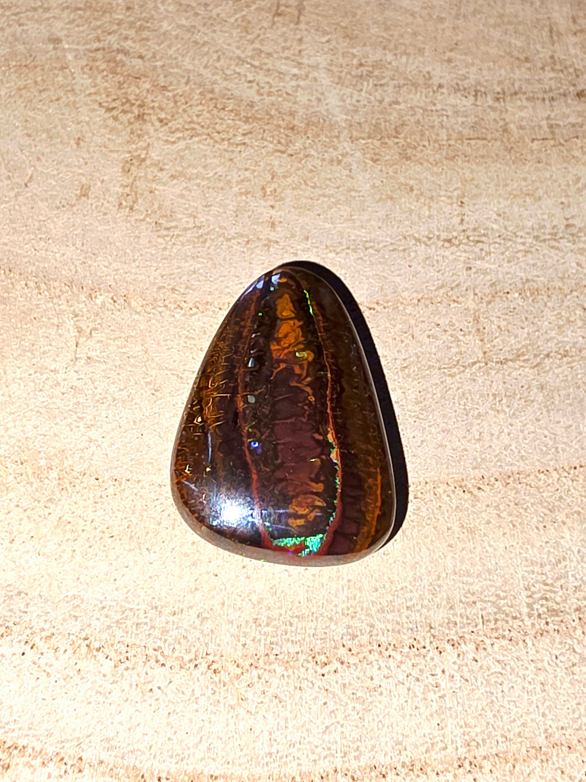 Polished gemstone on a beige wood background