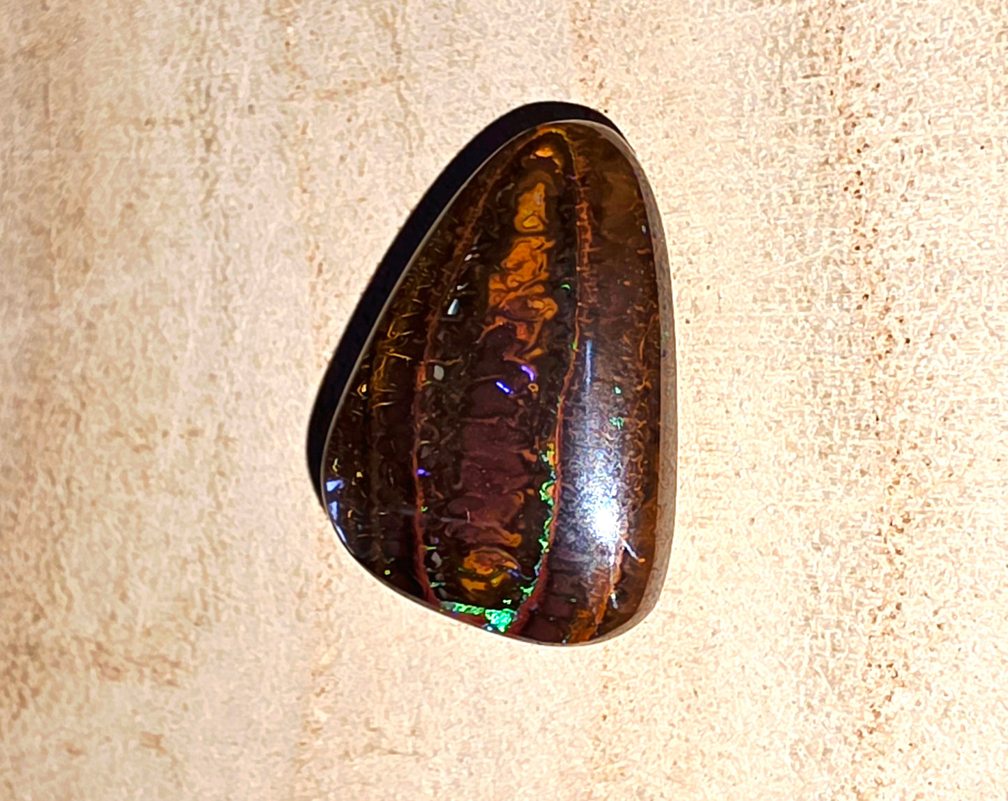 Polished opal stone on a beige fabric background