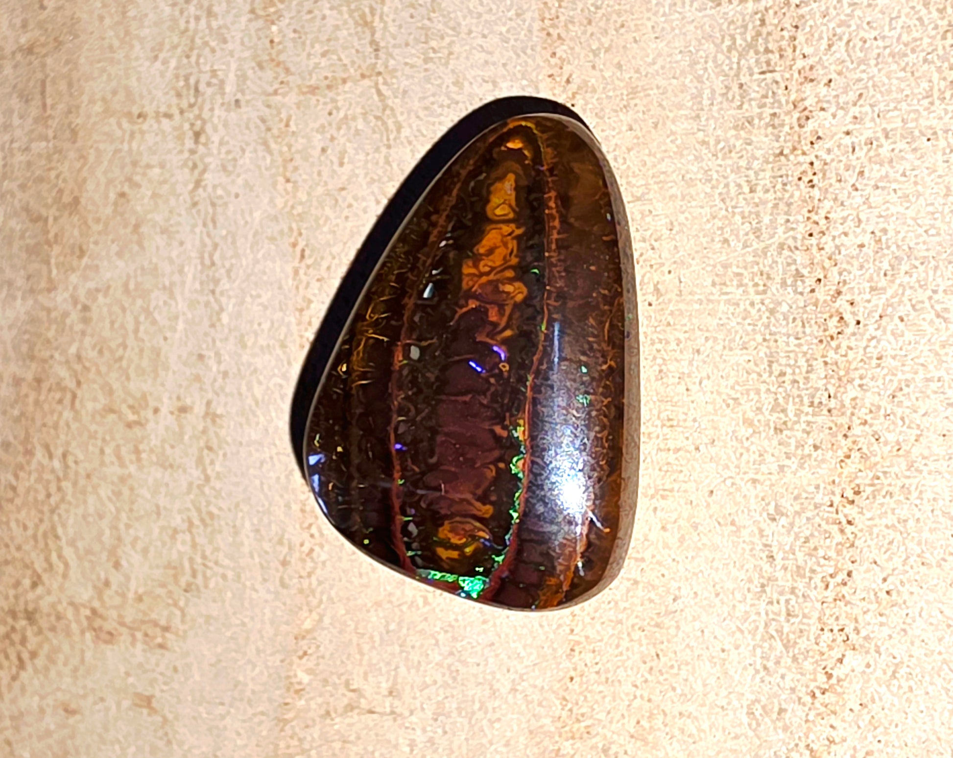 Polished opal stone on a beige fabric background