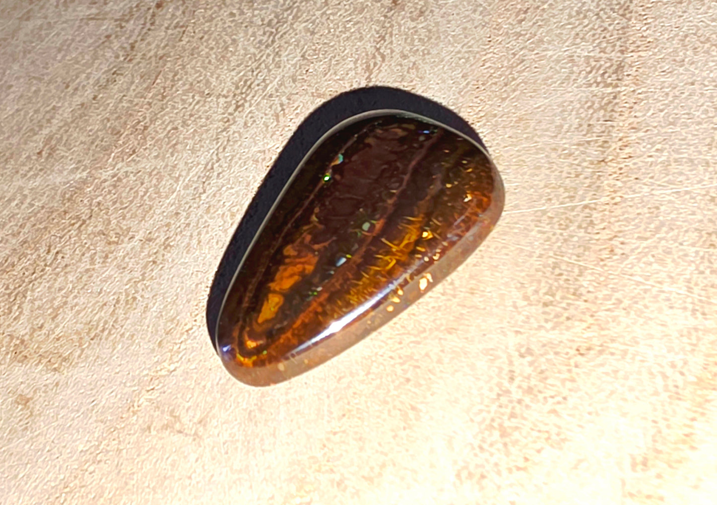 Polished opal stone on a beige background