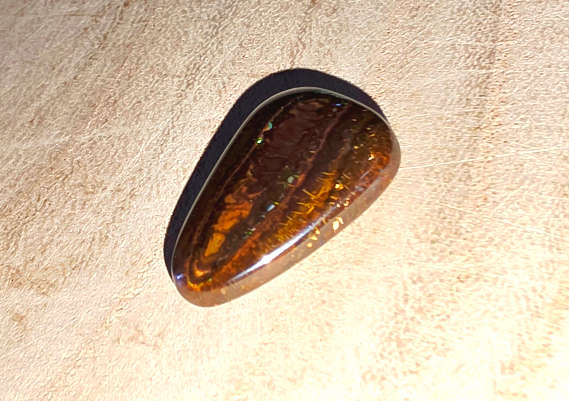 Polished opal stone on a beige background