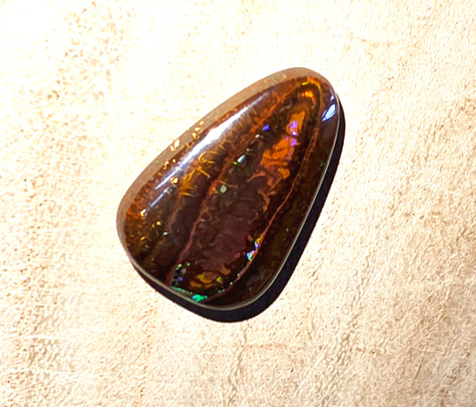 Polished opal stone on a beige background