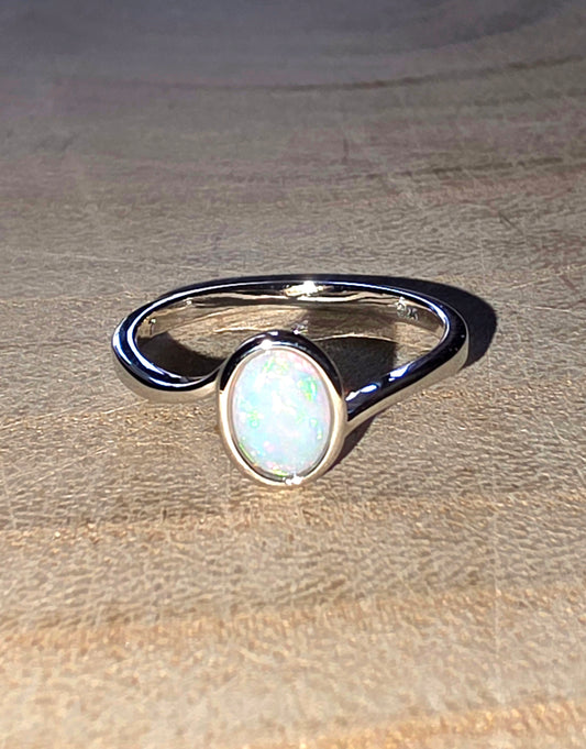 Silver ring with a white opal stone on a textured surface