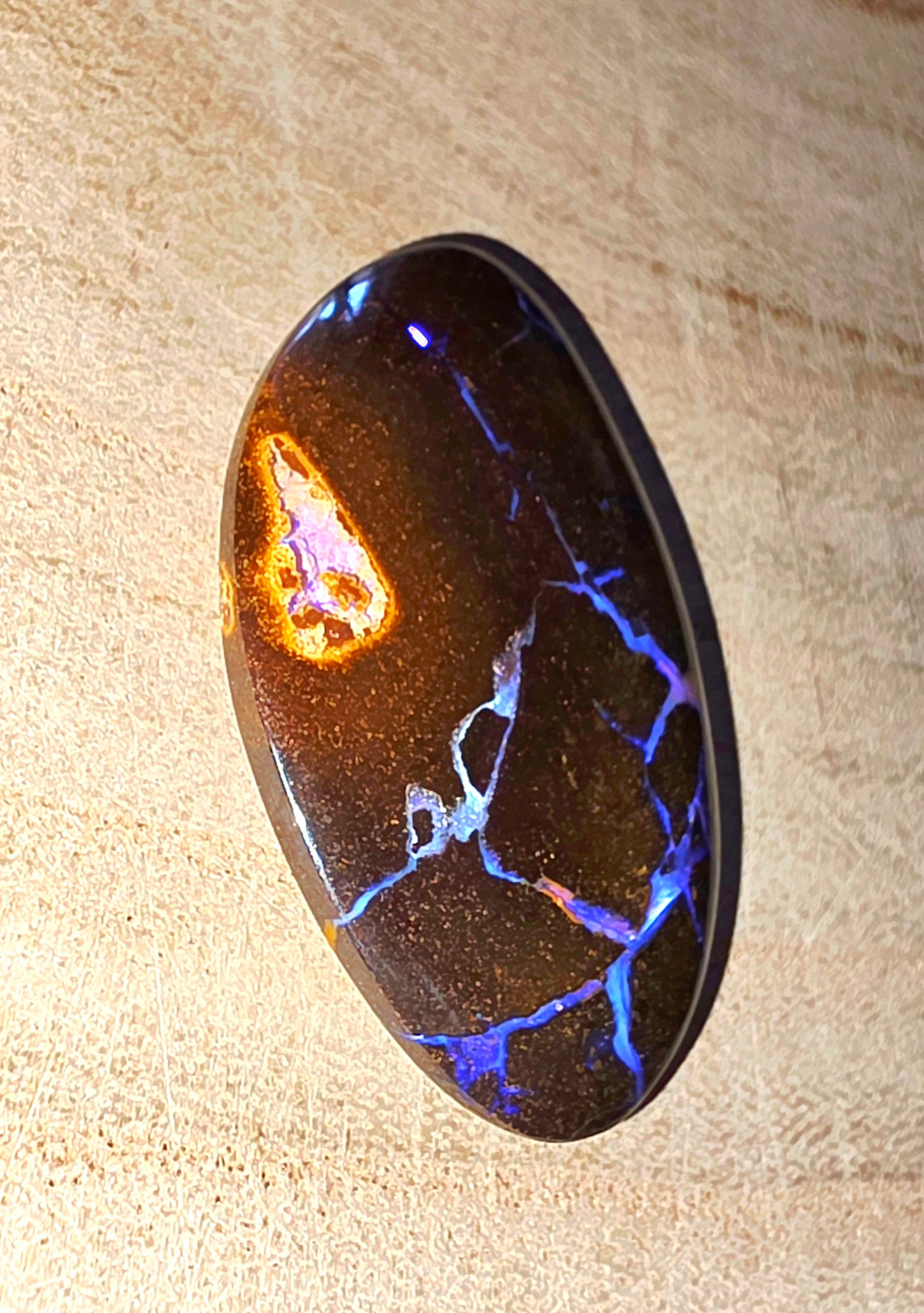 Polished stone with blue and orange fluorescence on a beige surface
