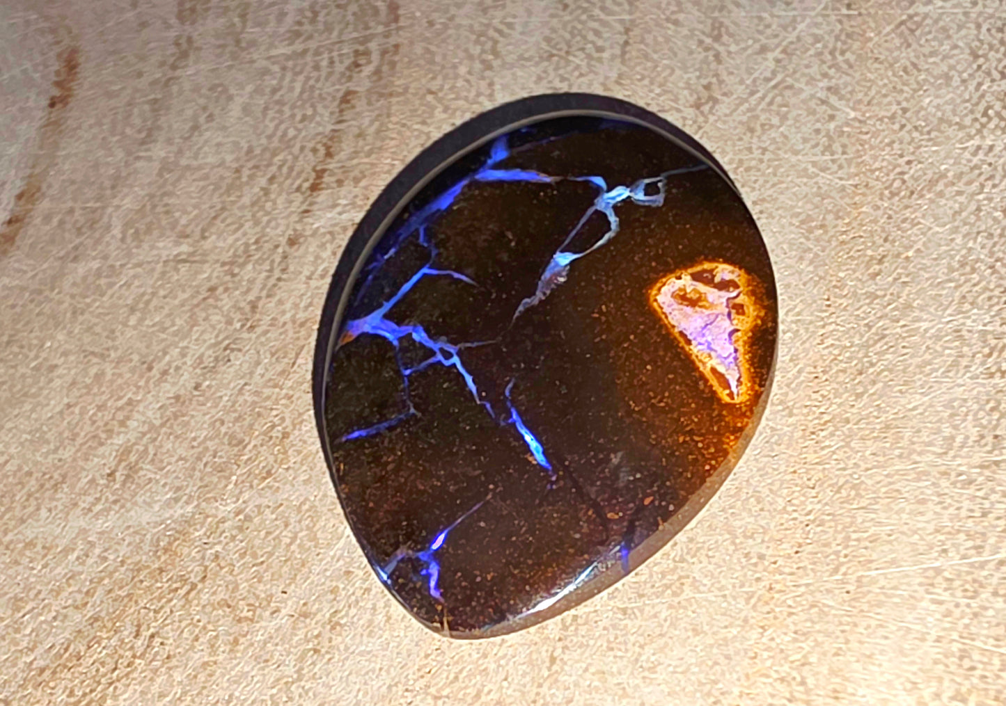 Polished stone with blue and purple fractures on a beige surface